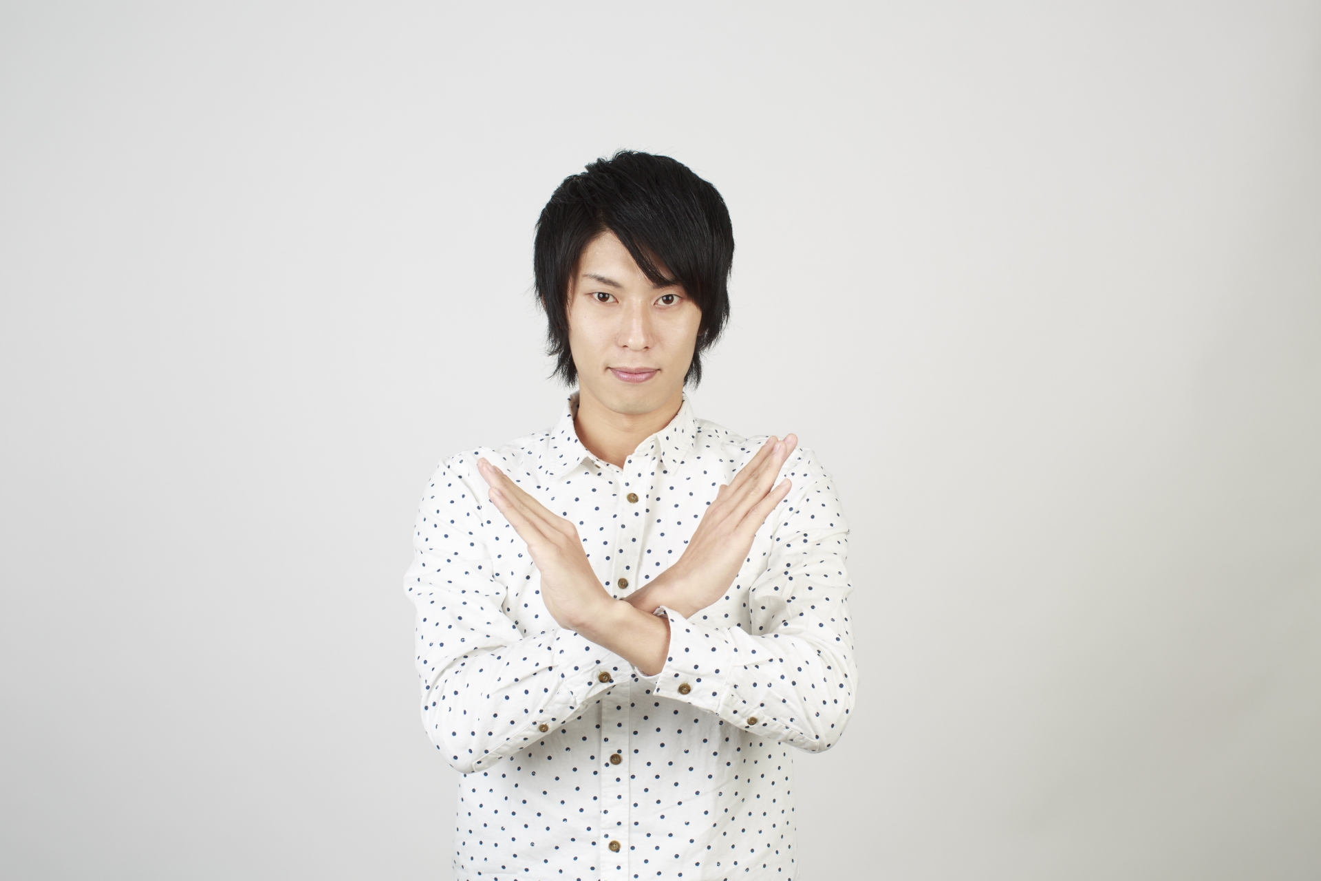 手でバツを作る男性