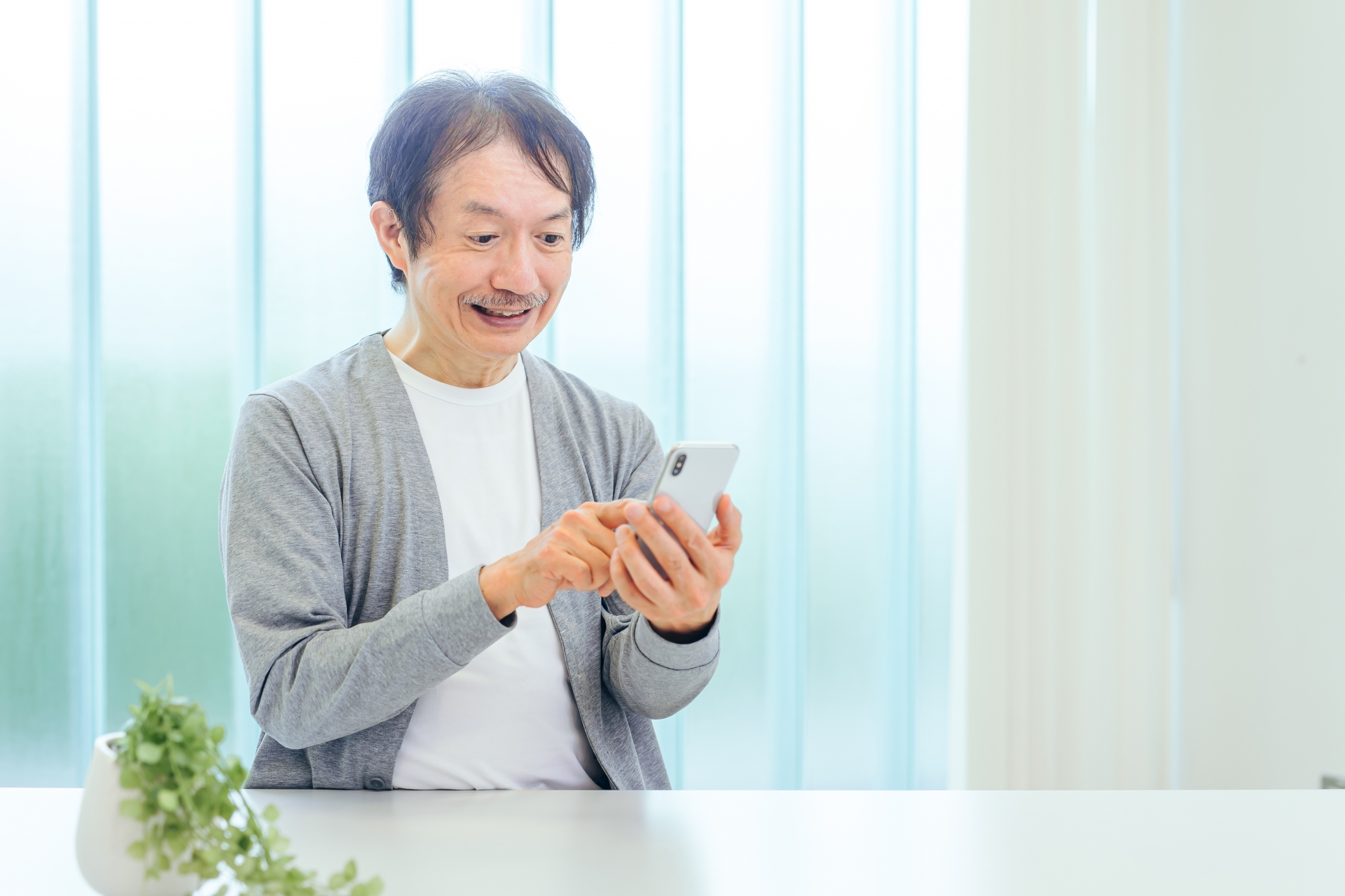 スマホを使う中高年男性（アプリ・笑顔）