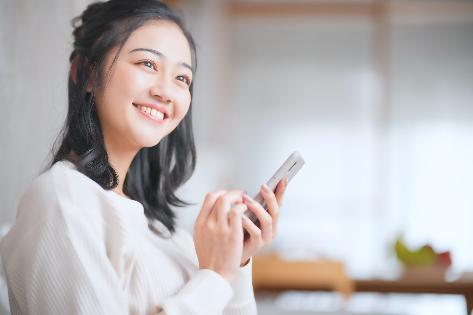 スマホを持ち笑顔で見つめる女性