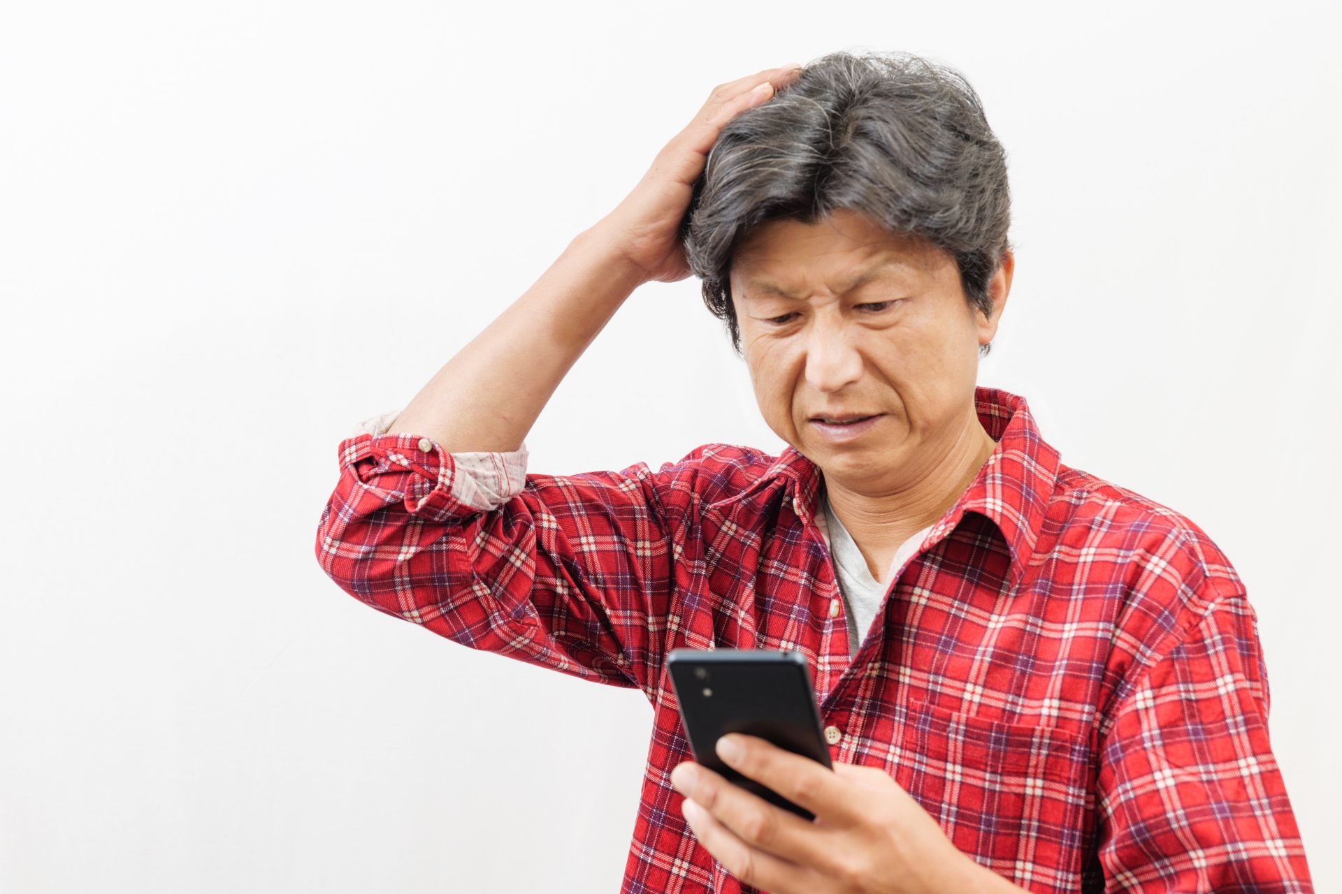 スマートフォンを見て困った顔をする男性