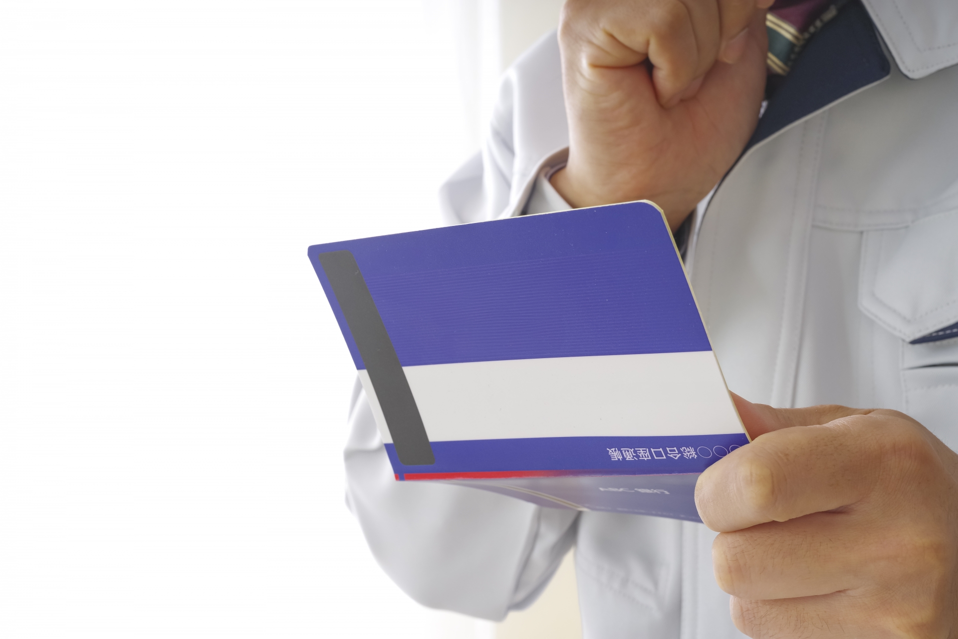 通帳を見つめる作業服の男性