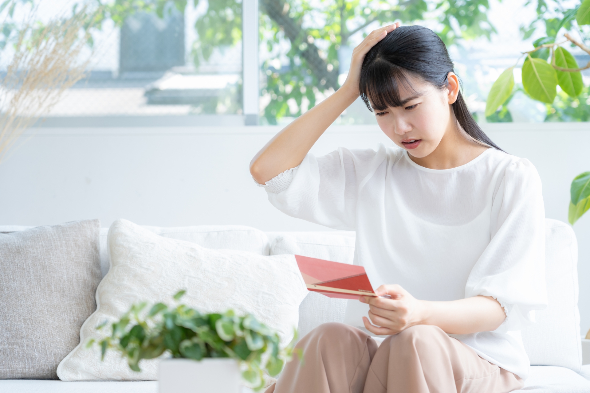 リビングで貯金通帳を見る若い女性