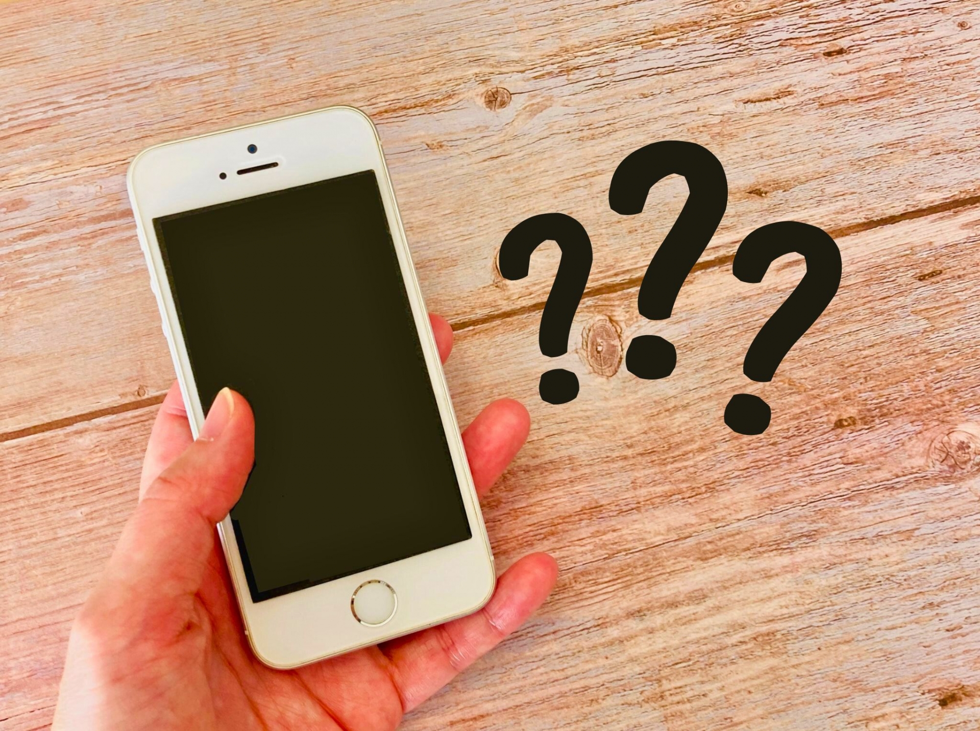 スマホを持つ手元とクエスチョンマーク