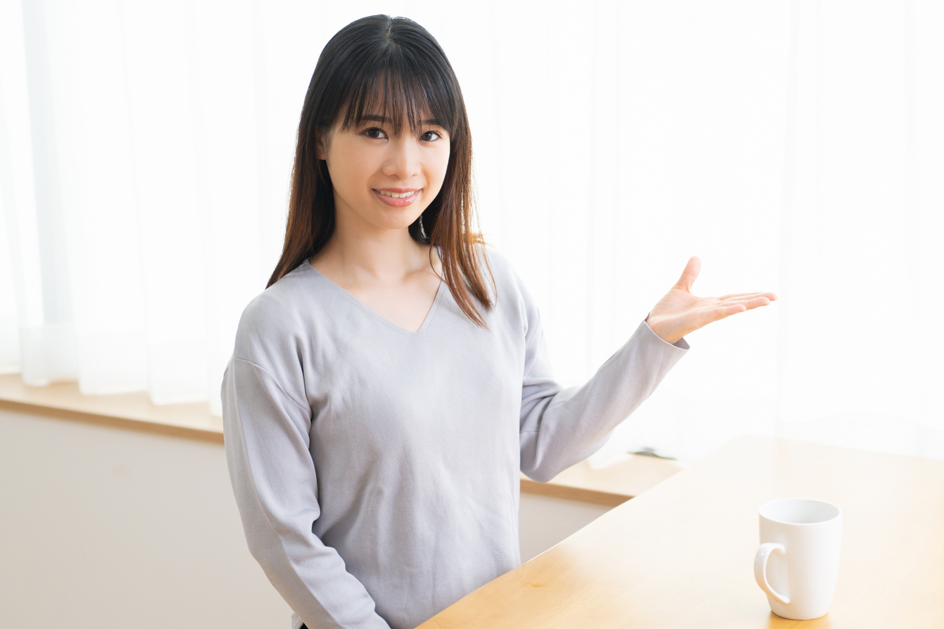 案内のポーズをする若い女性