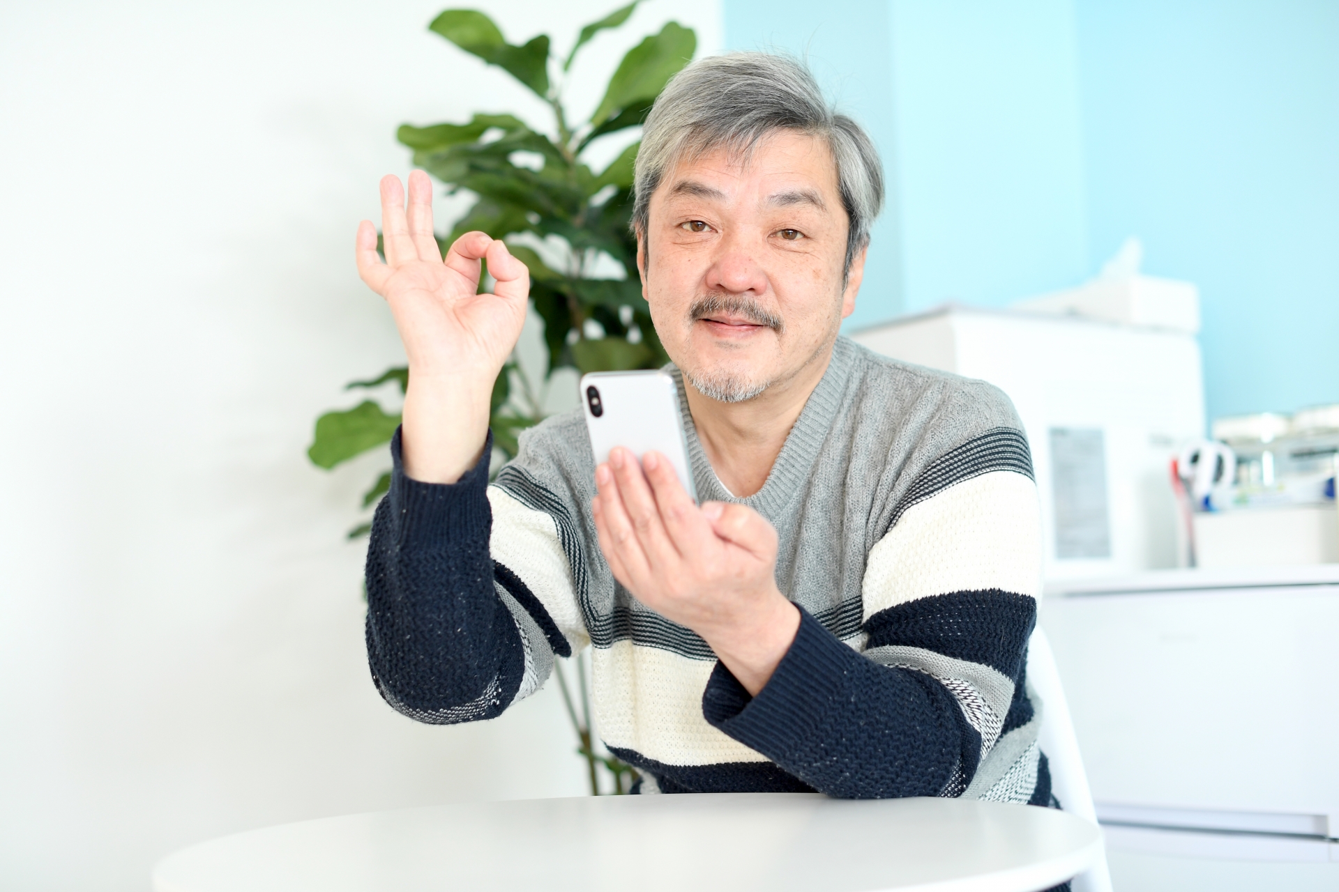 OKサインを出してスマホを操作する男性