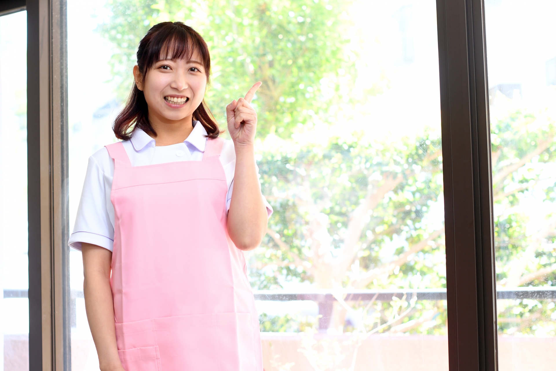 指差しをするエプロン姿の若い女性