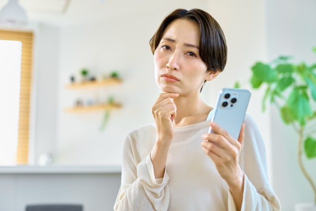 携帯を持って考える女性