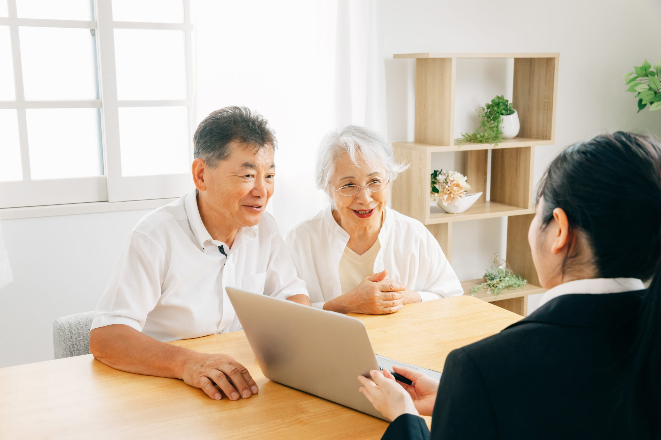 パソコンで説明する女性と高齢者夫婦