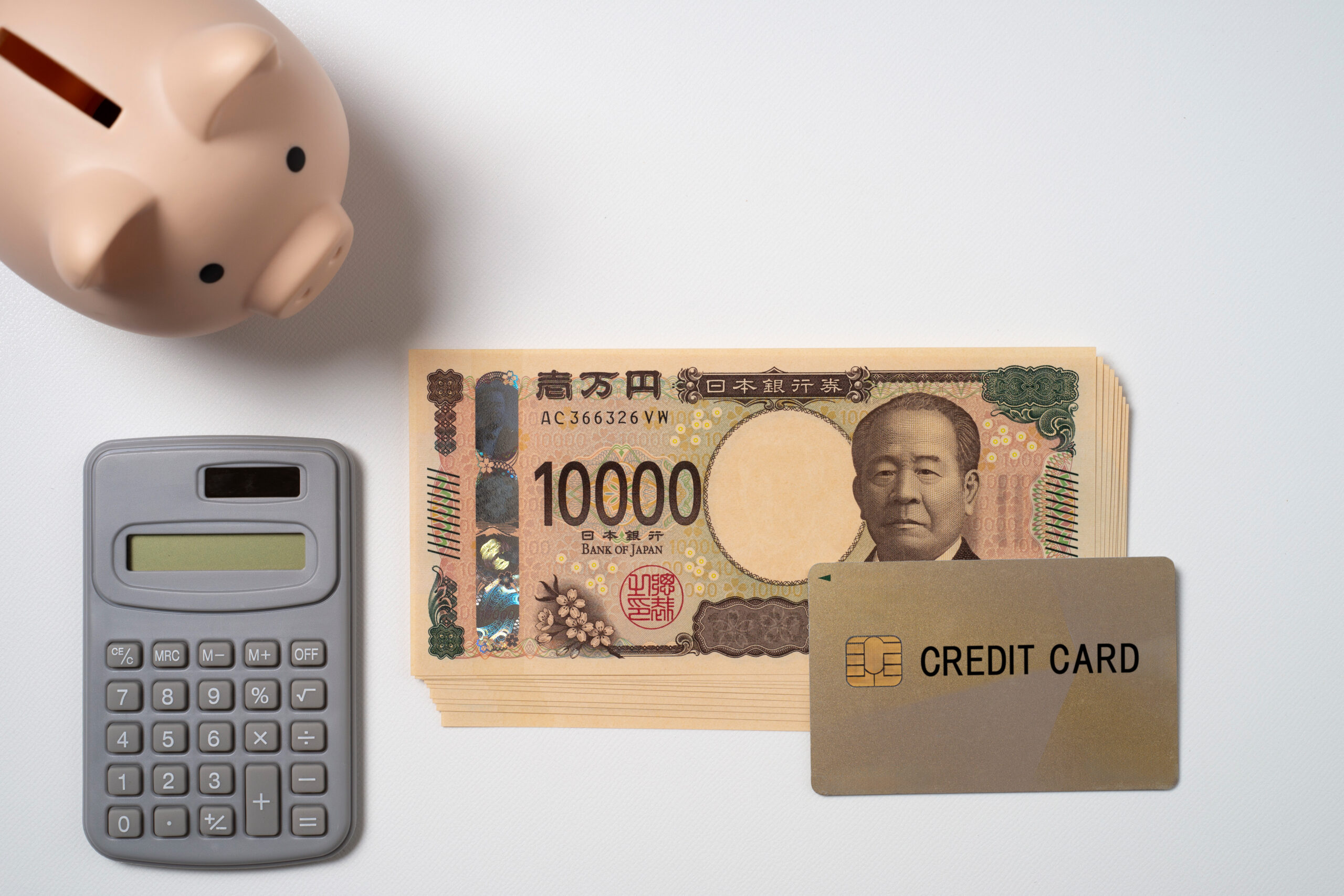 クレジットカードと一万円札と電卓と貯金箱
