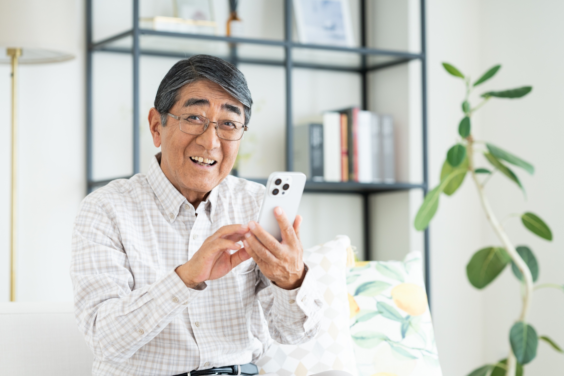 家でスマホを使うシニアの男性