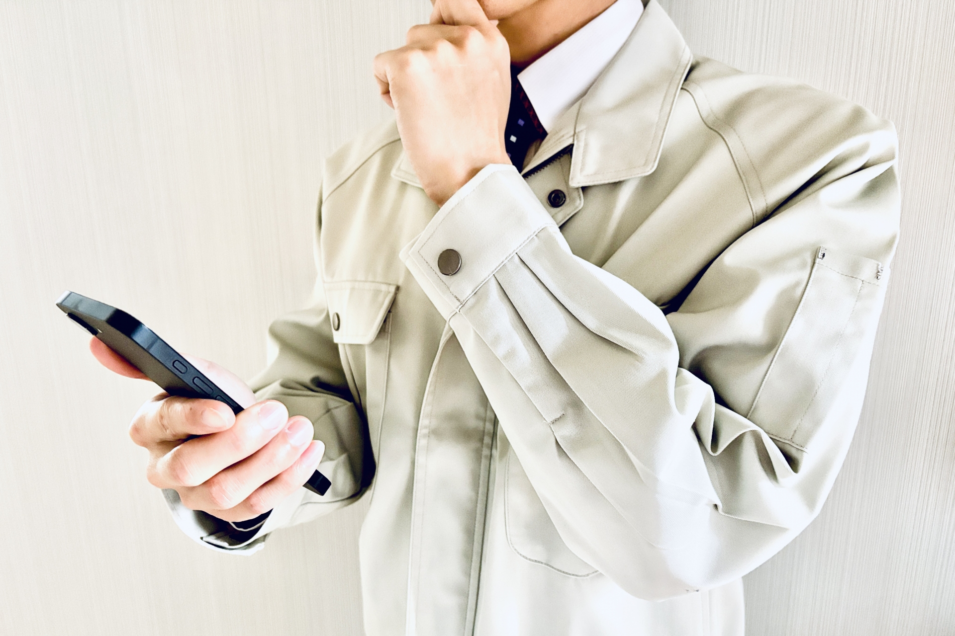 スマホを見て悩む作業着姿の男性
