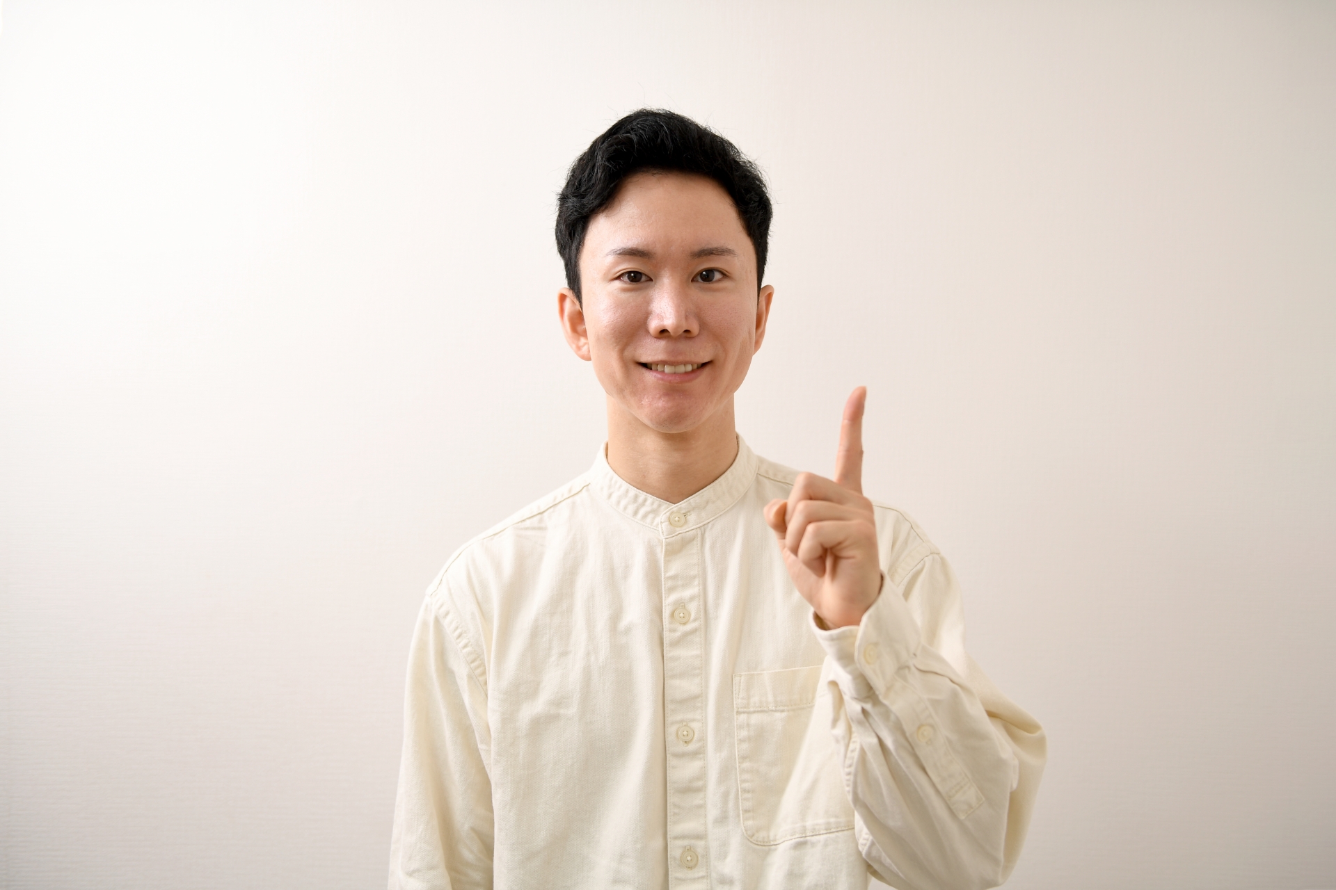 人差し指を振るう笑顔の私服のアジア人男性