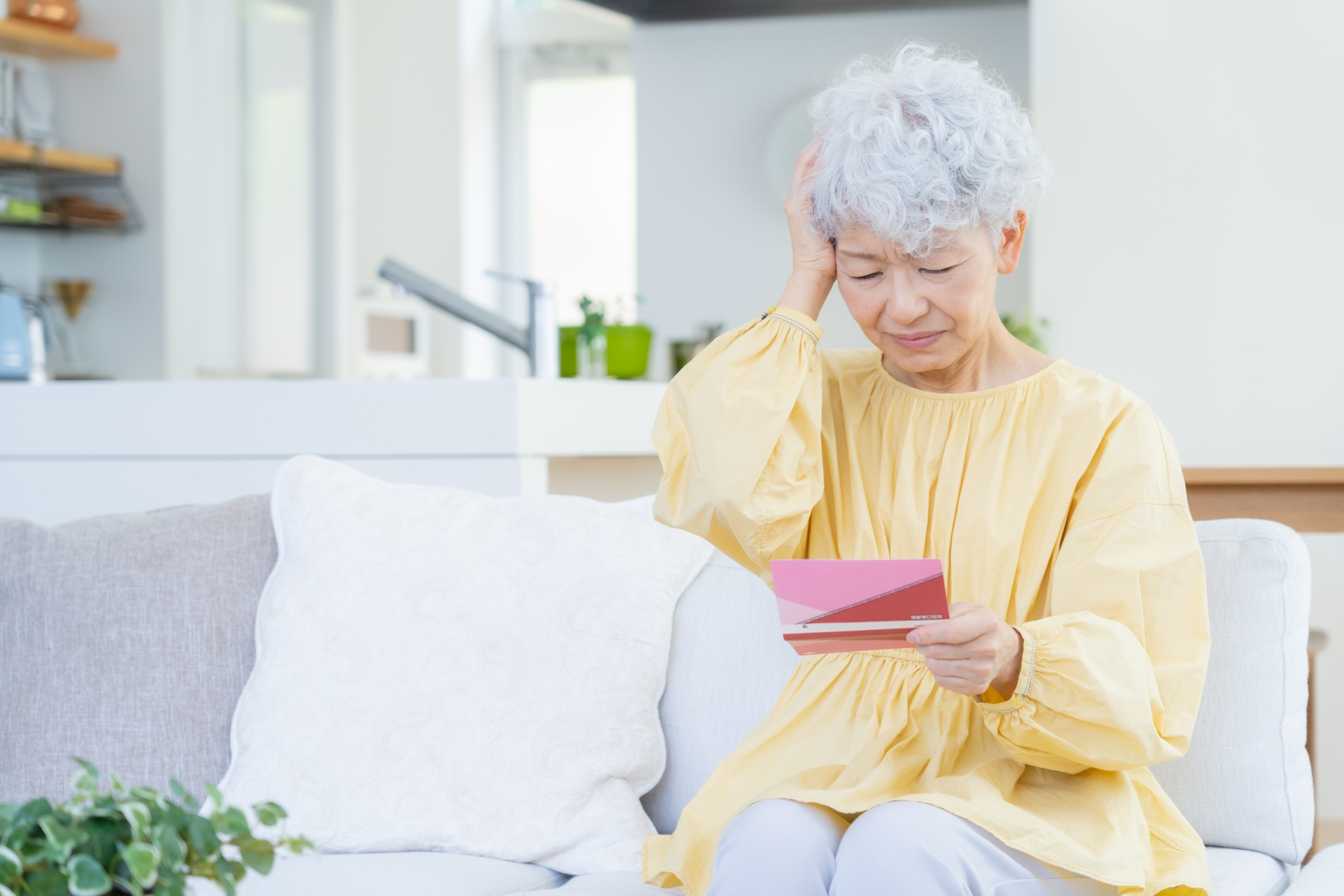 通帳を見て悩む高齢女性