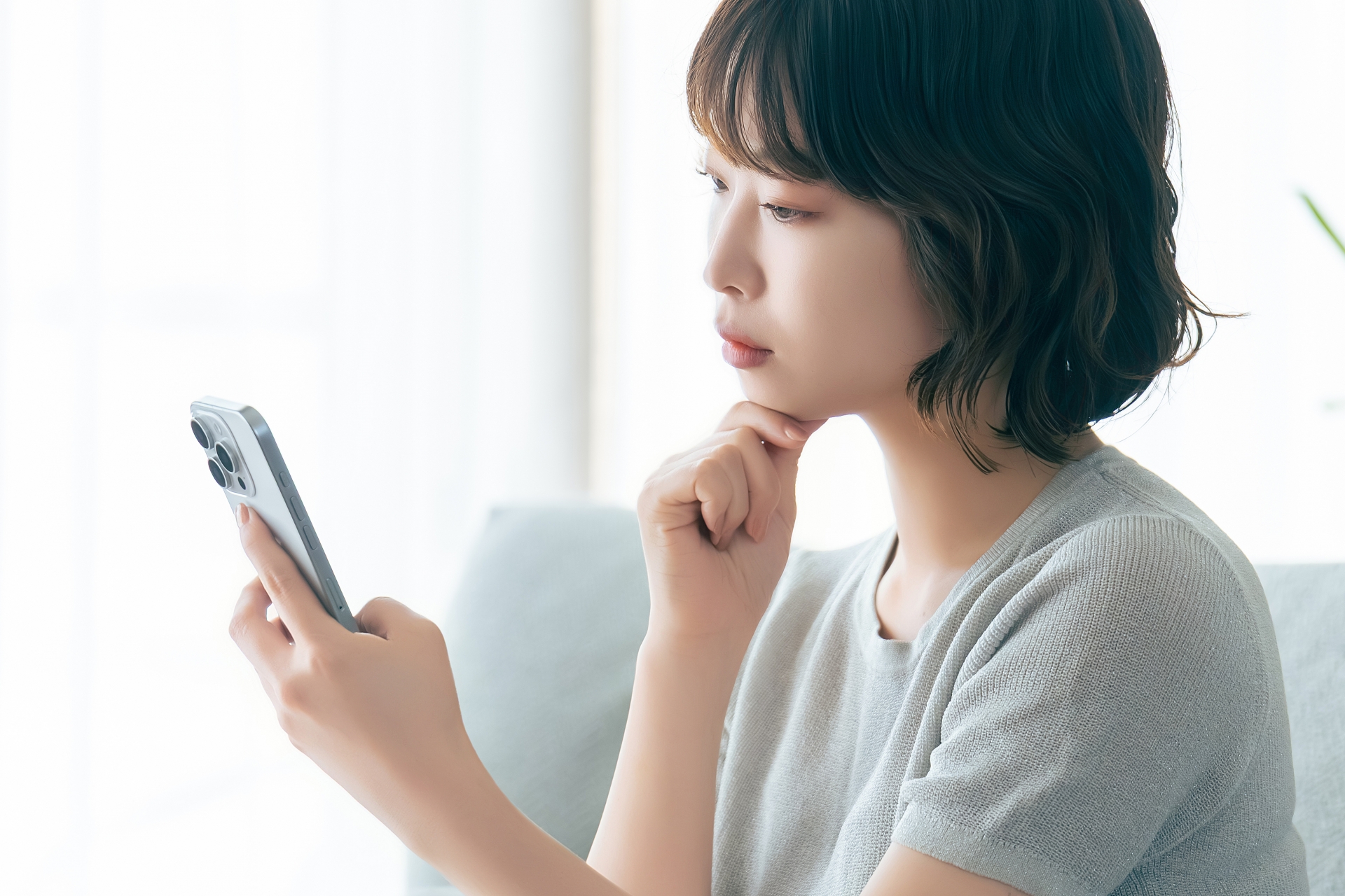 スマホを見ながら考えごとをする女性