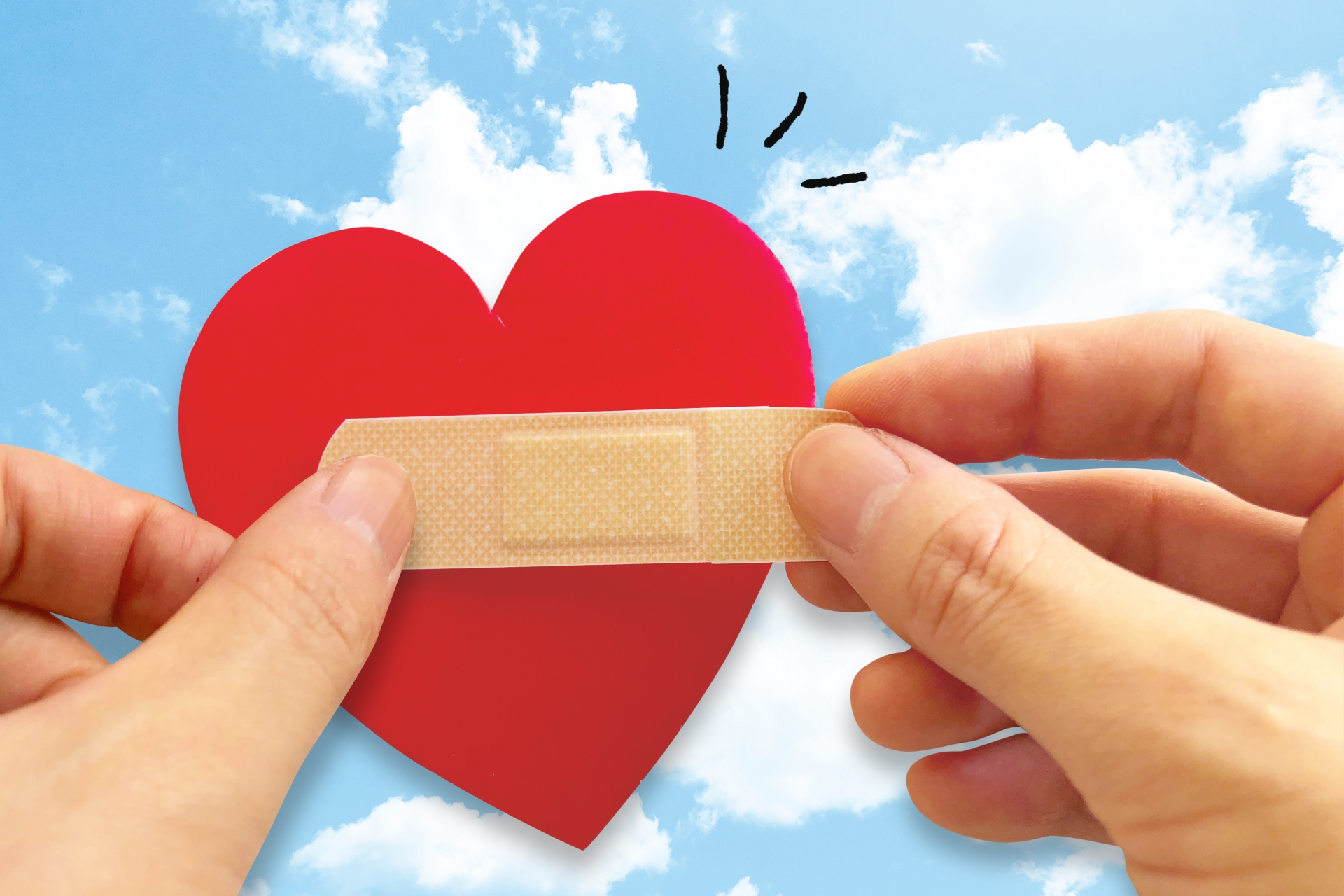 傷ついた心にバンドエイドを貼る　青空の背景