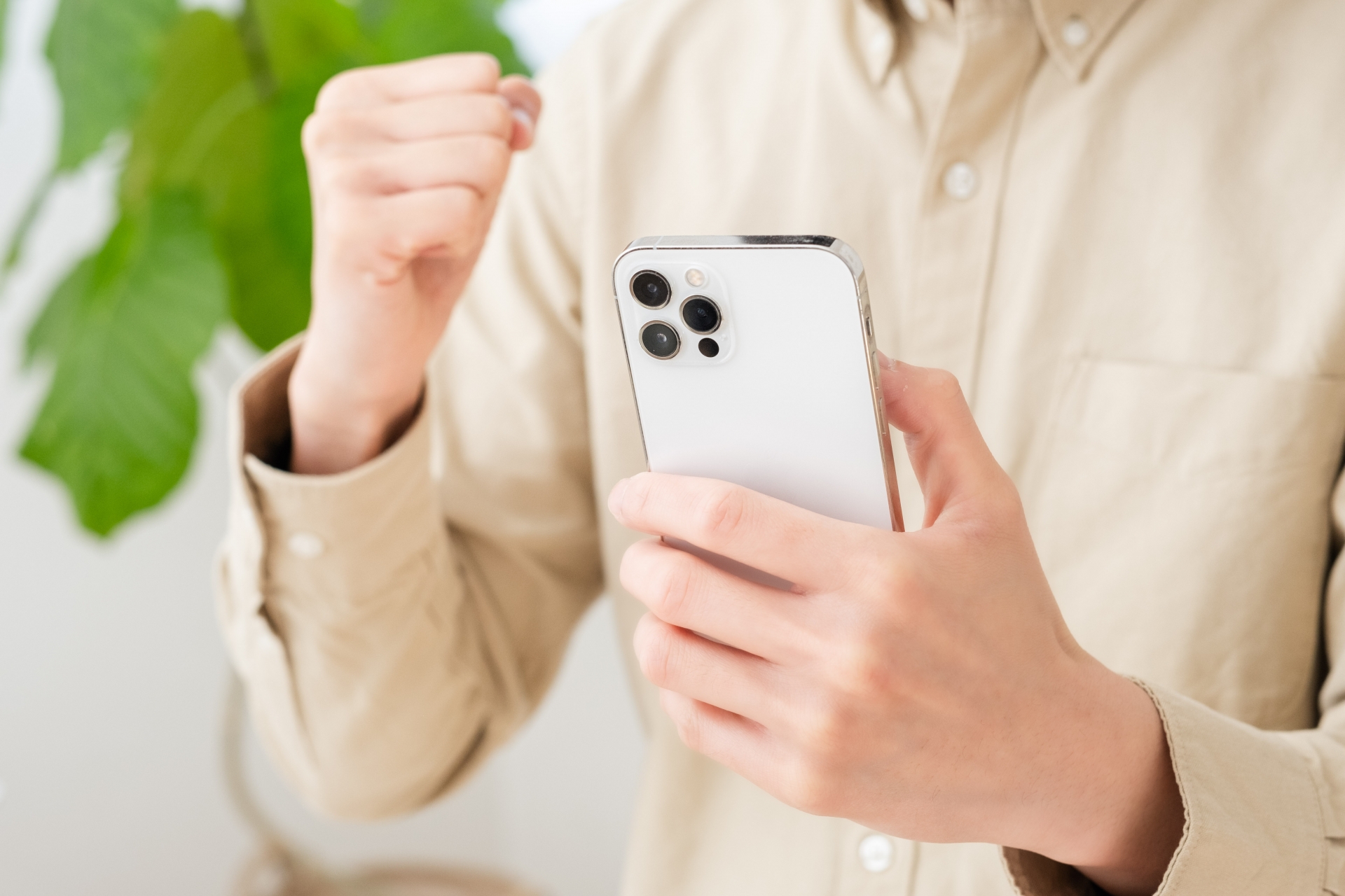 スマホを持ってガッツポーズする男性