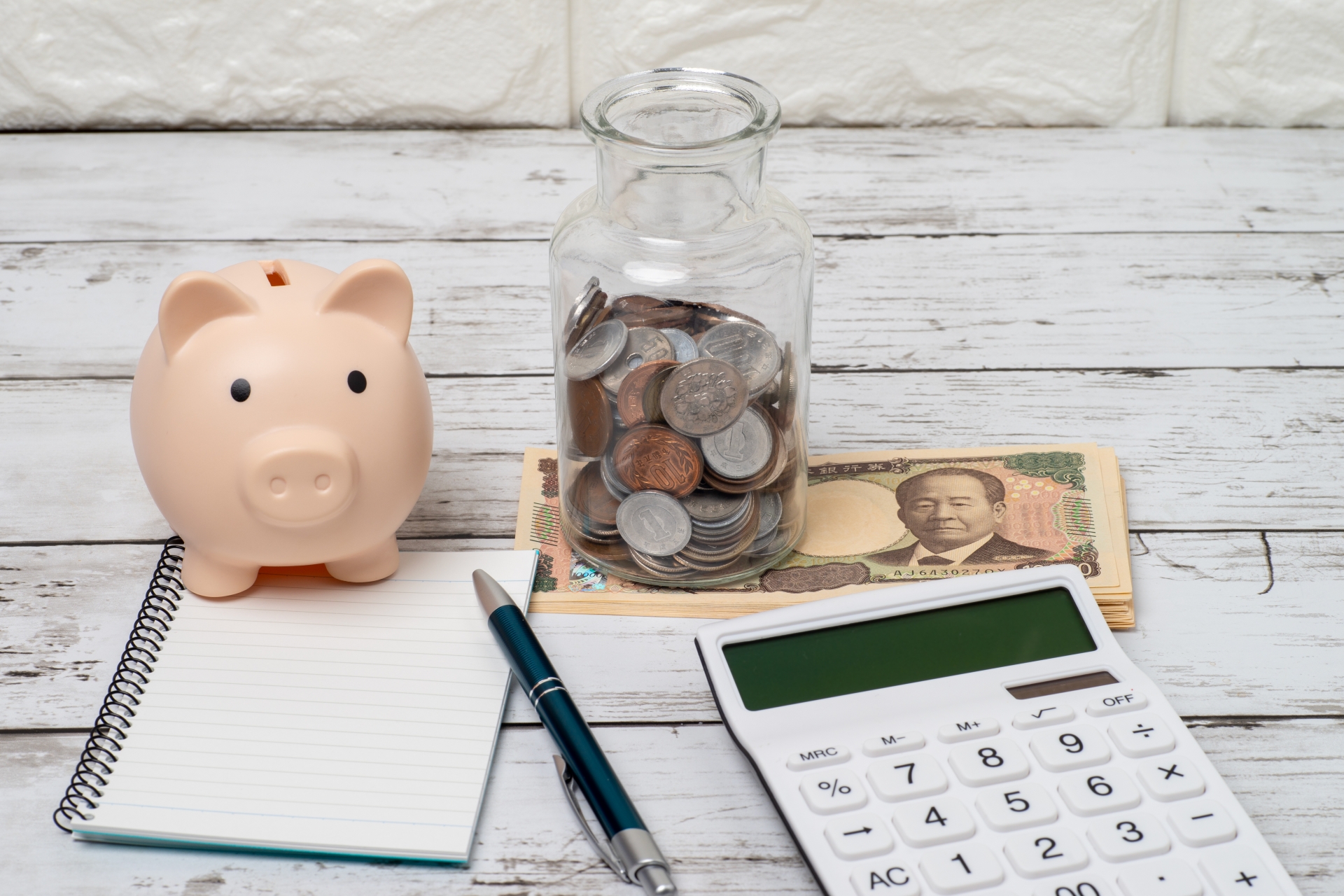 貯金箱と瓶の小銭と電卓とノートとお金