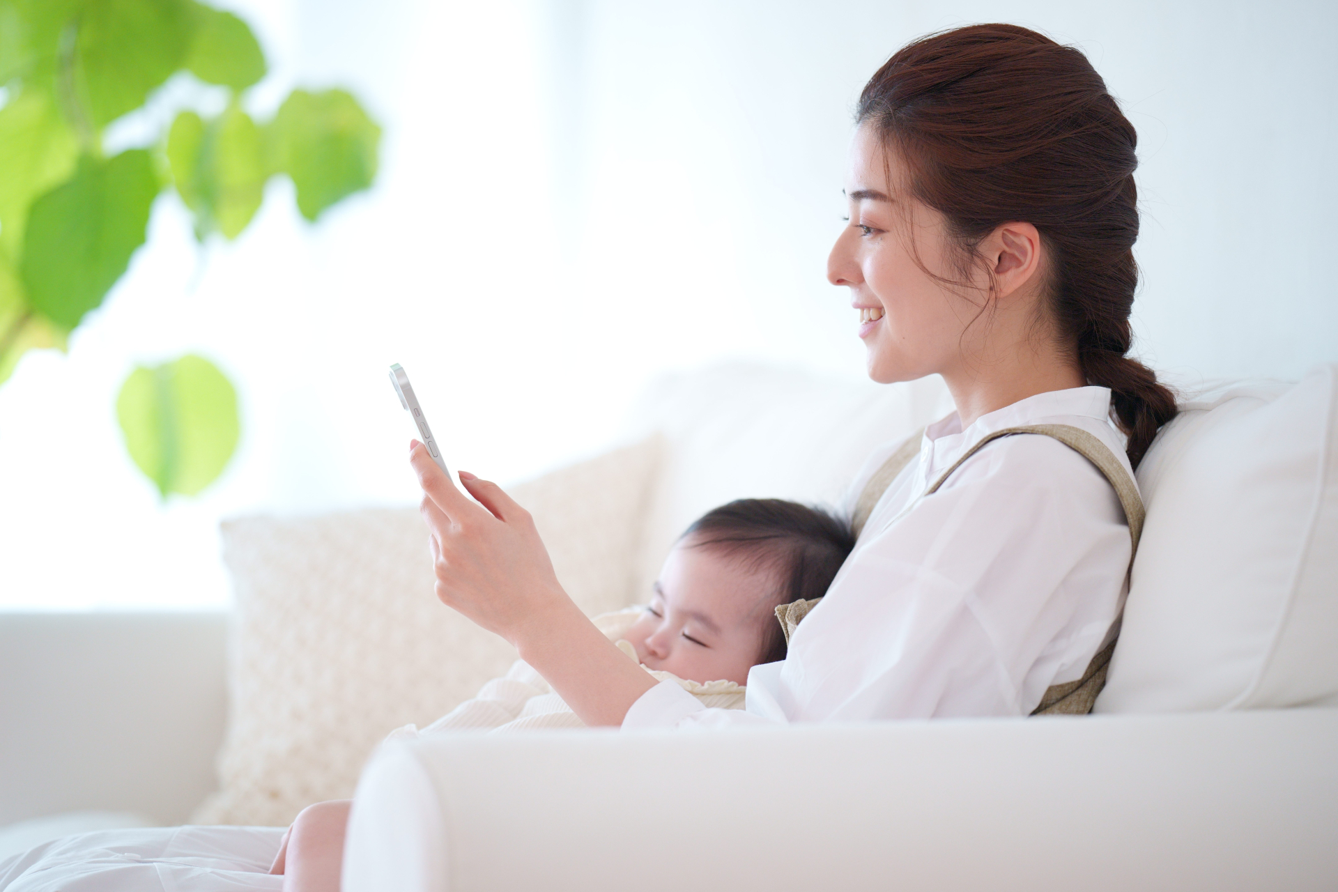 赤ちゃんを抱っこしてスマホを見る女性