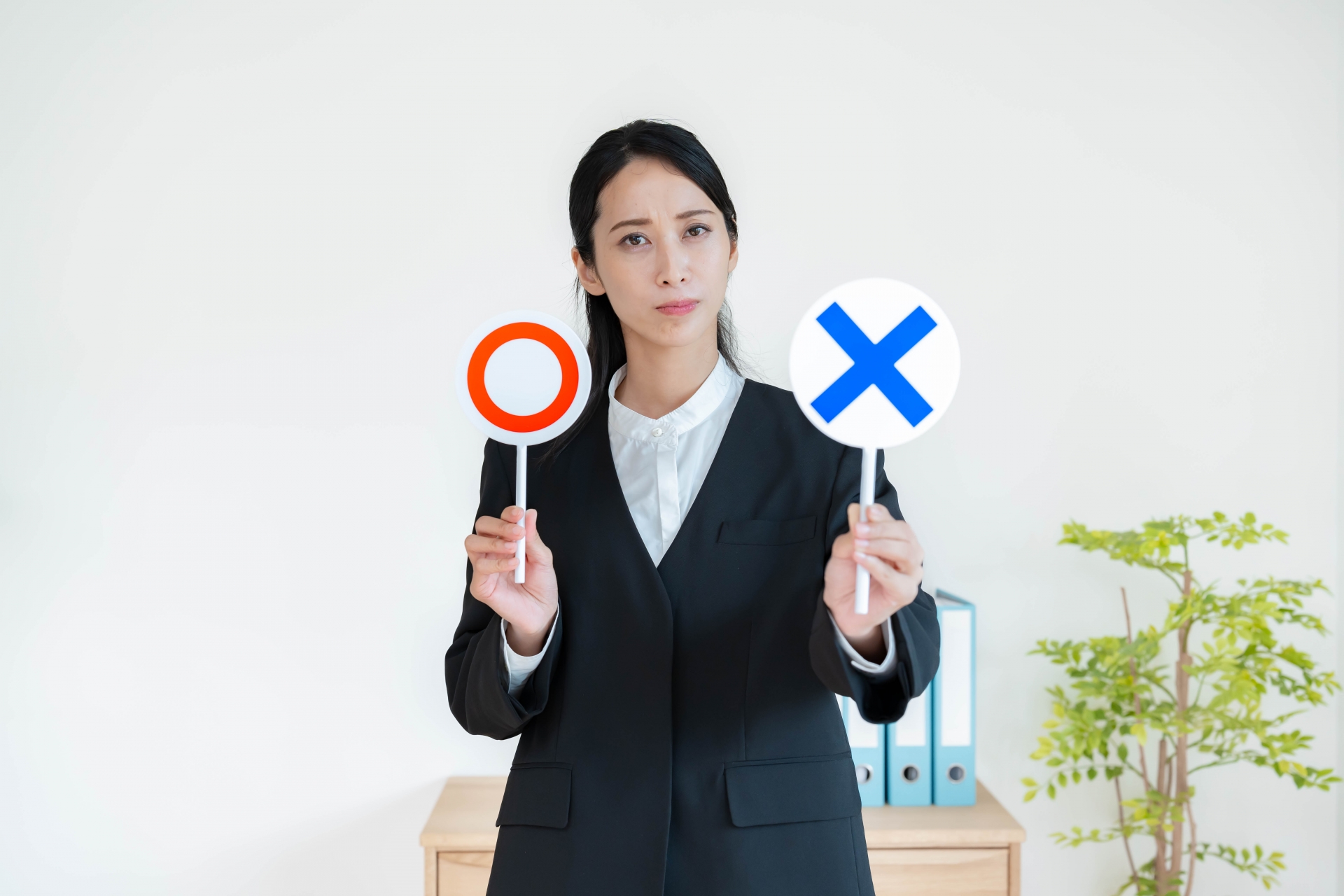 まるとバツの札を持つ女性