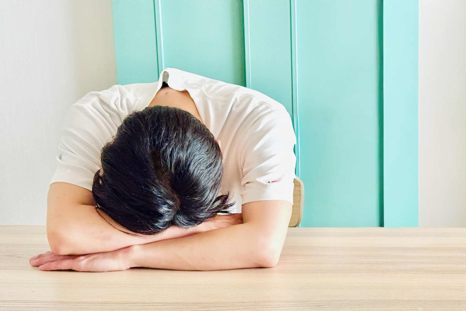 顔を隠して机に伏せる男性