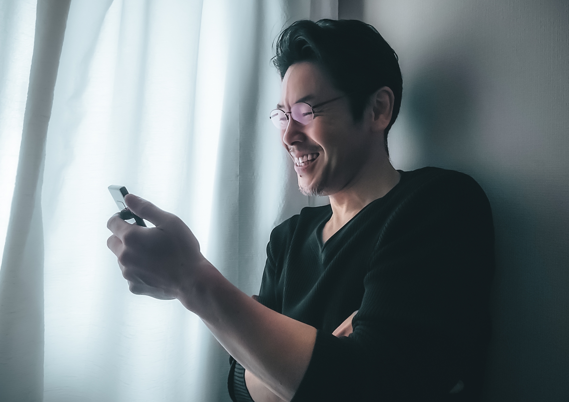 笑みを浮かべてスマホを持つミドルの男性