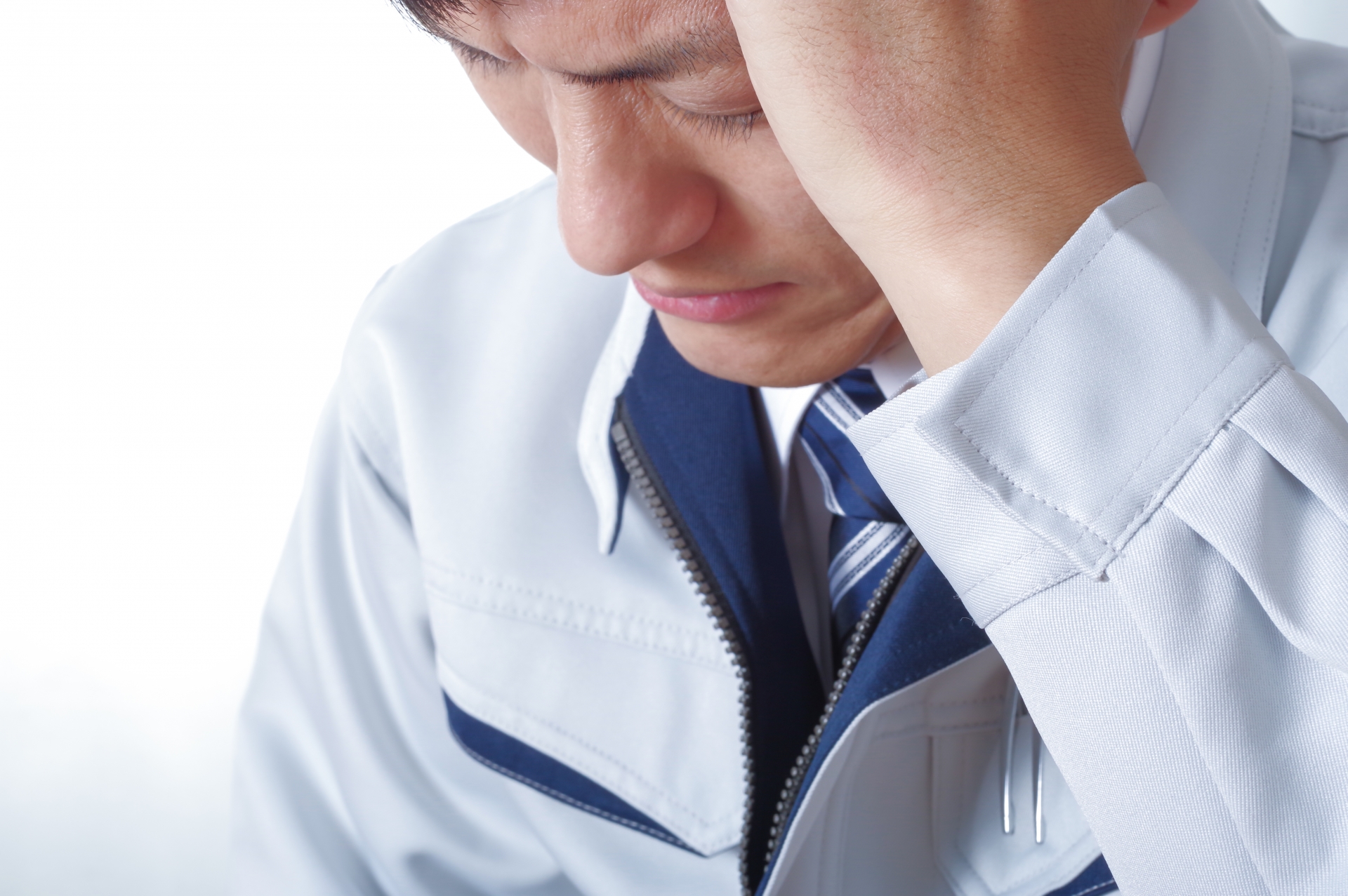 考え事をする作業服の男性