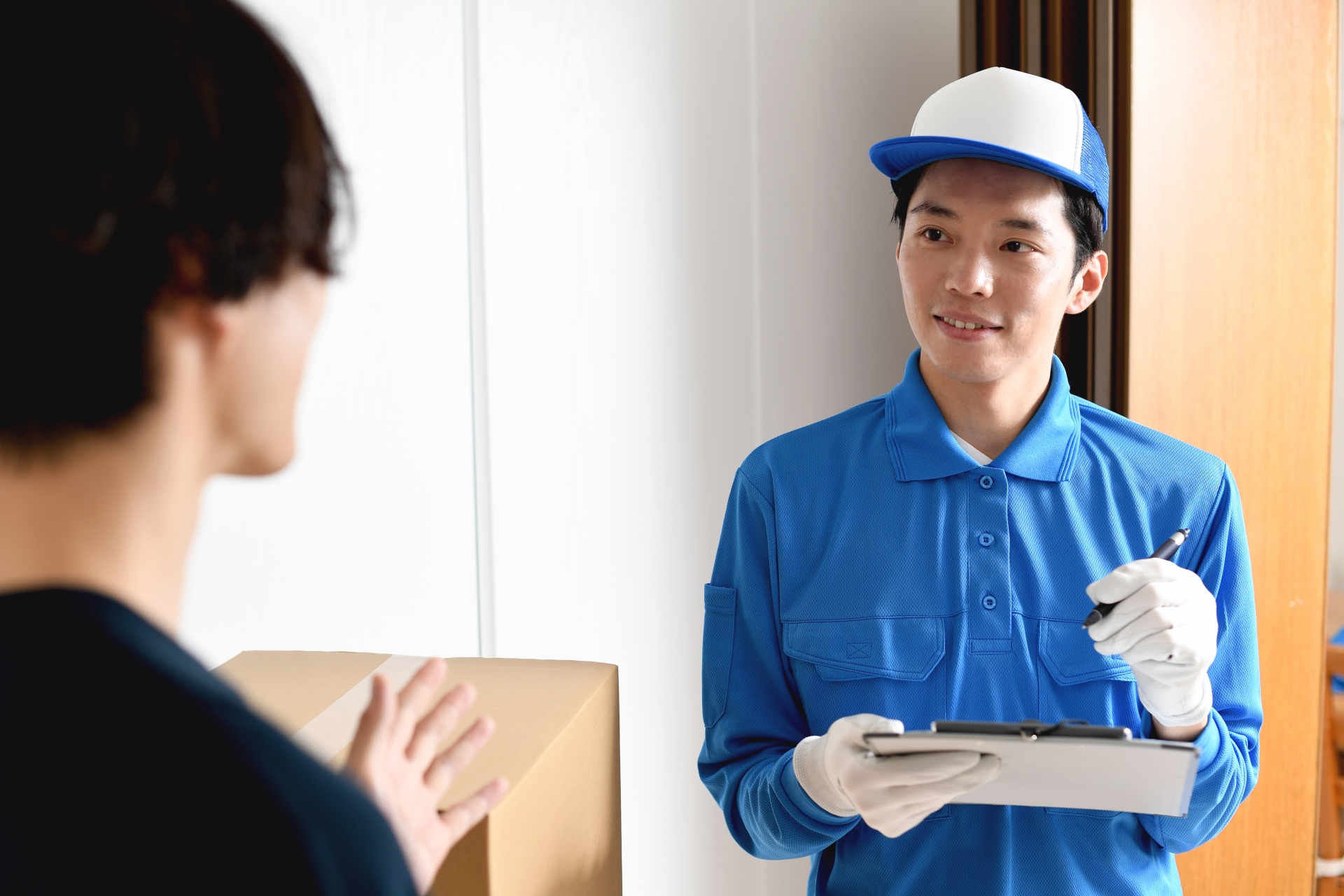 部屋で会話をする男性作業員と若い男性客