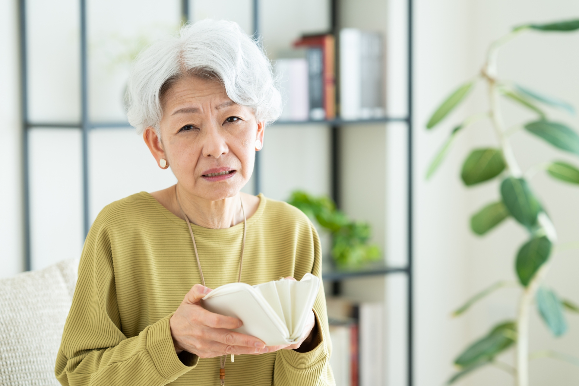 財布を持って悩むシニアの女性