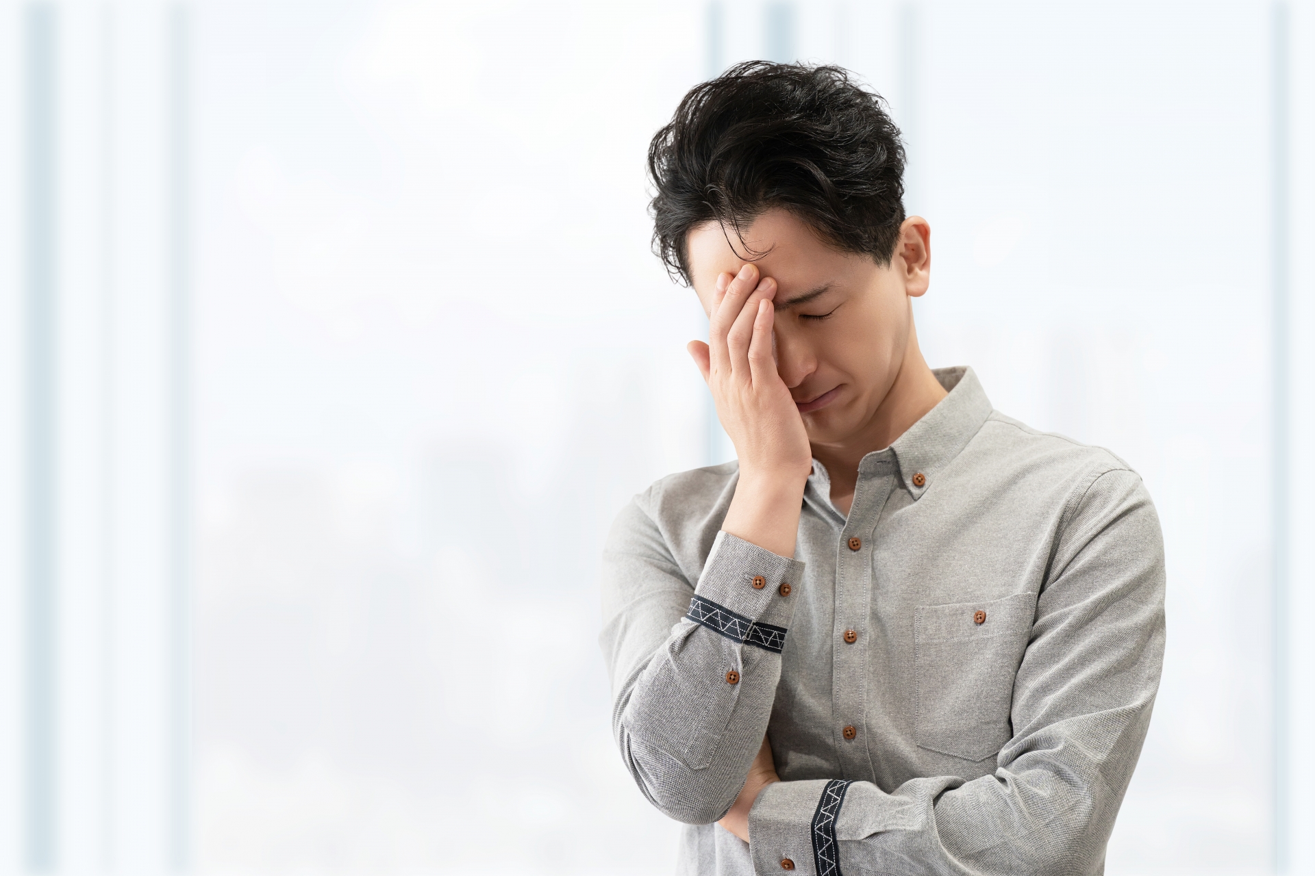 顔を覆って悩む男性