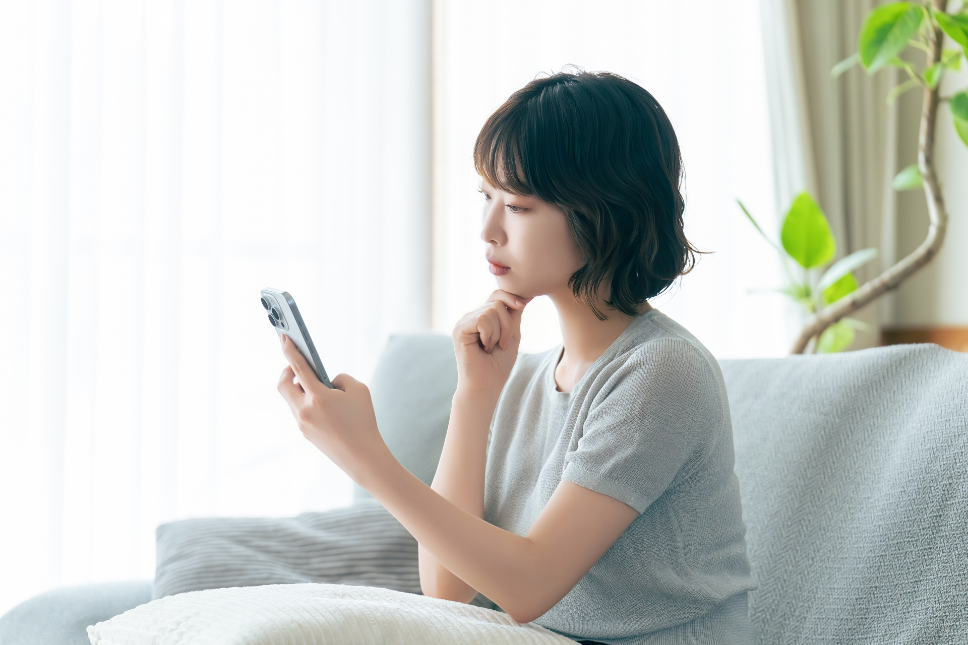 スマホを見て考えごとをする女性