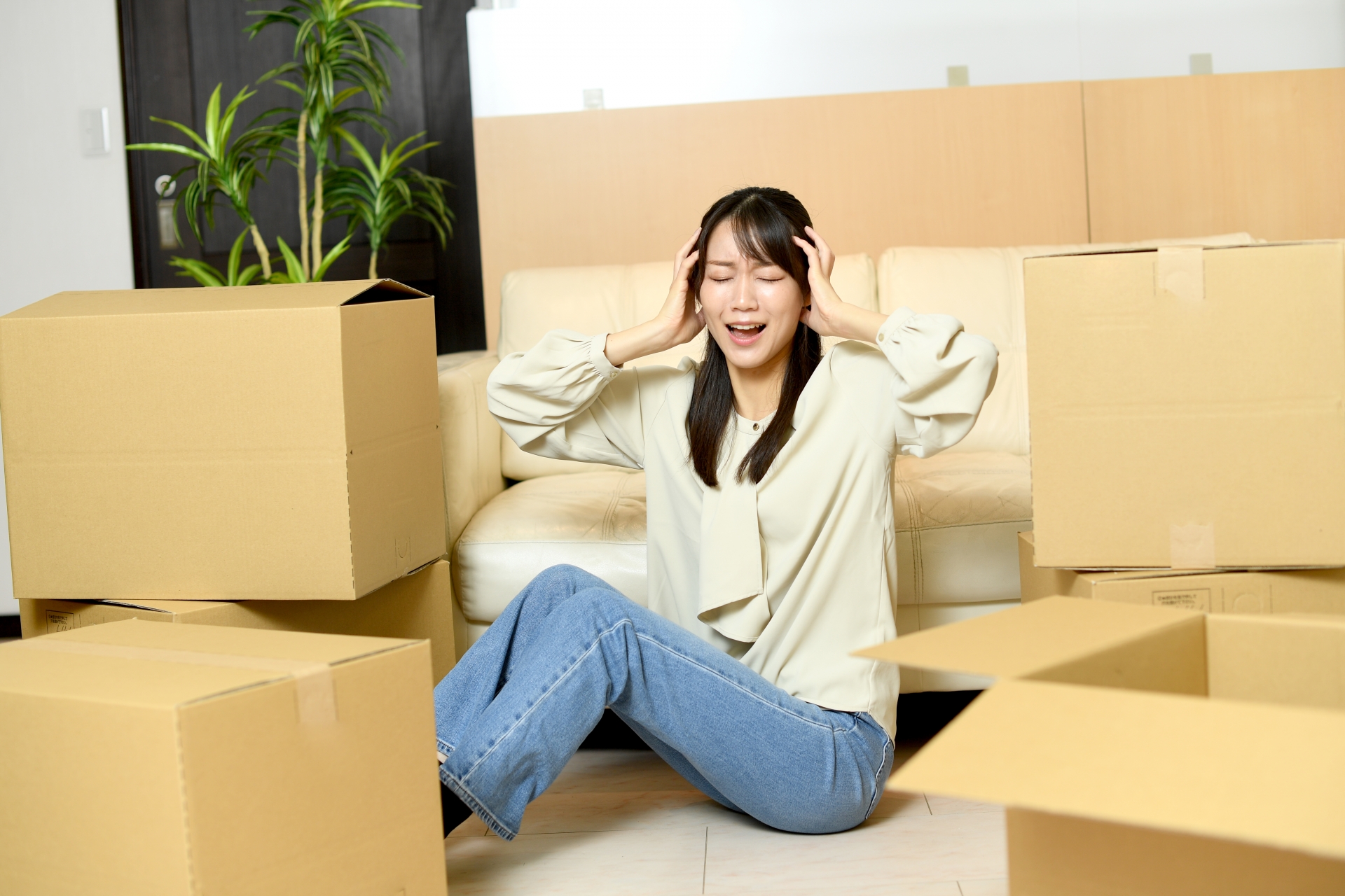 段ボール箱の前で困る若い女性