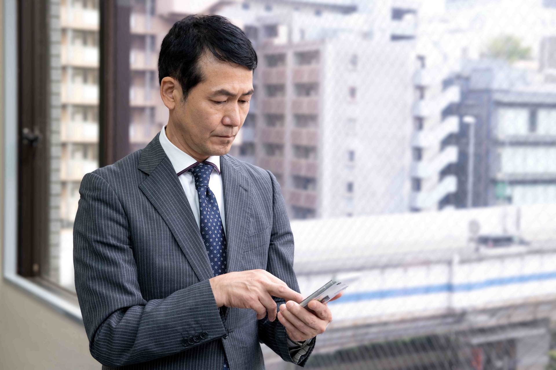 窓際でスマホを使う会社員