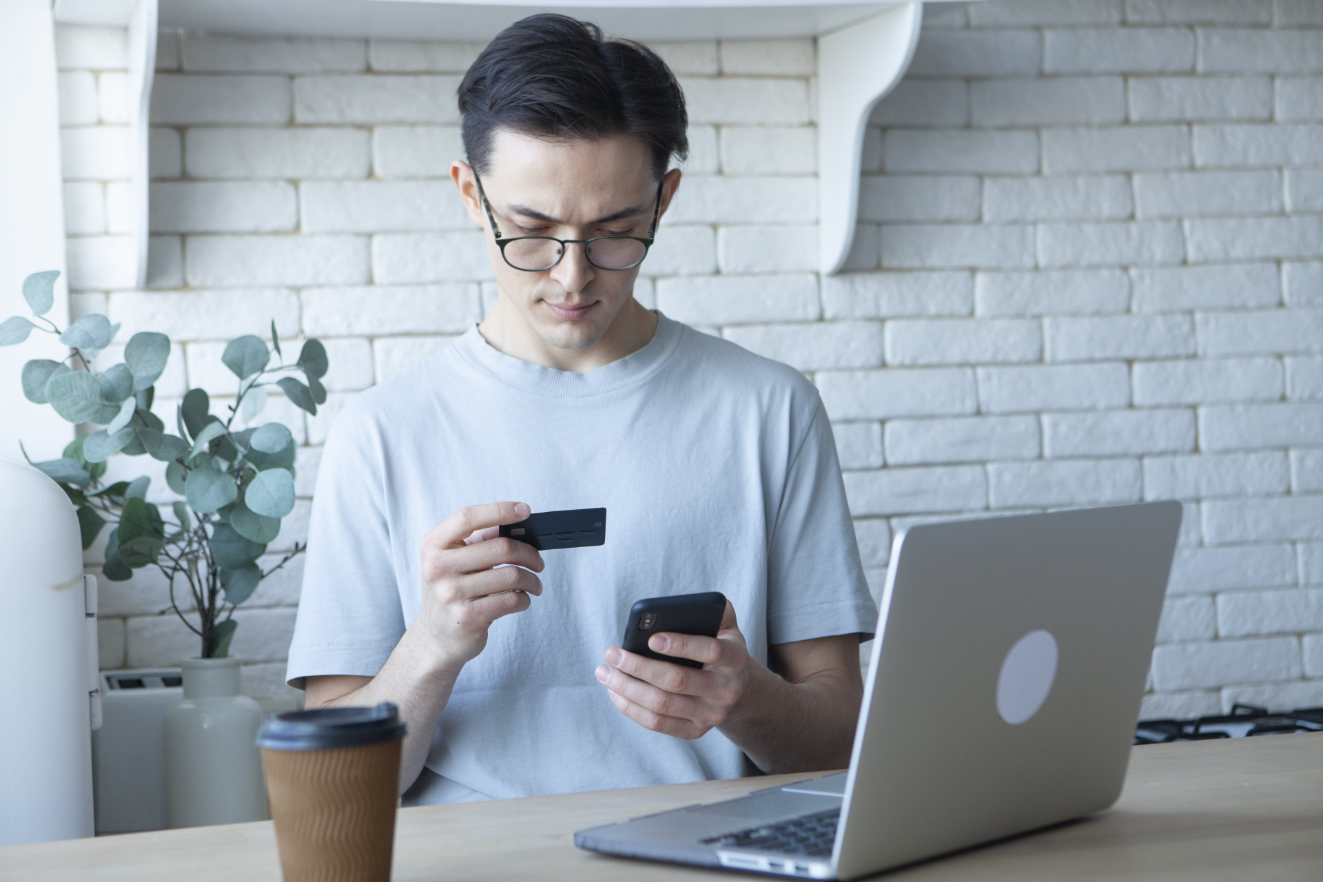 クレジットカードを見ながらスマホで入力す男性