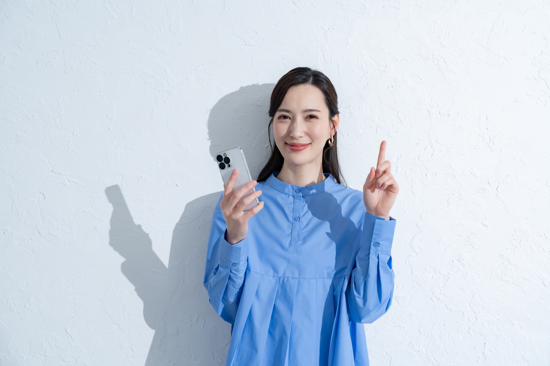 携帯を持つ青いワンピースを着た女性