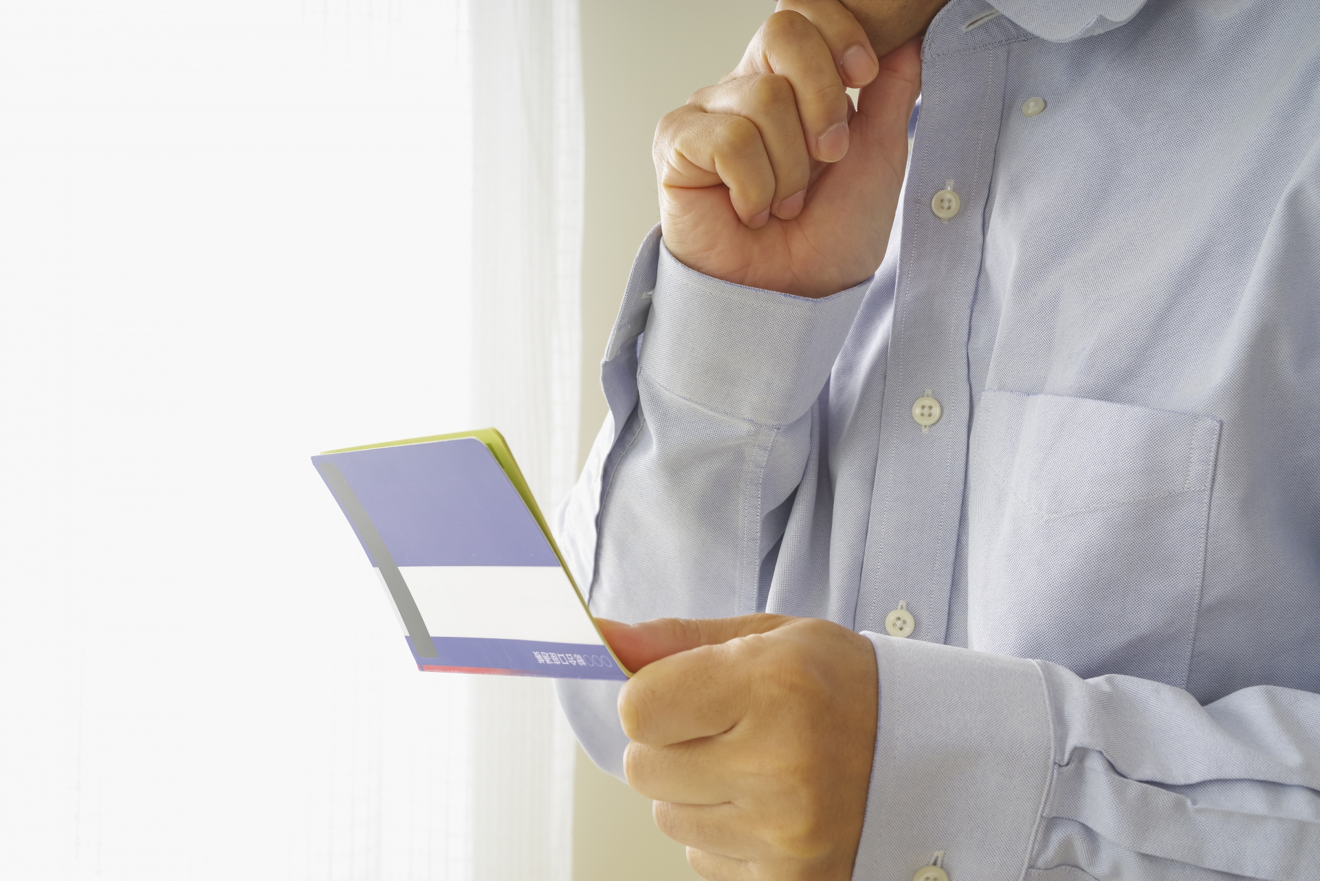 通帳を見て悩む男性