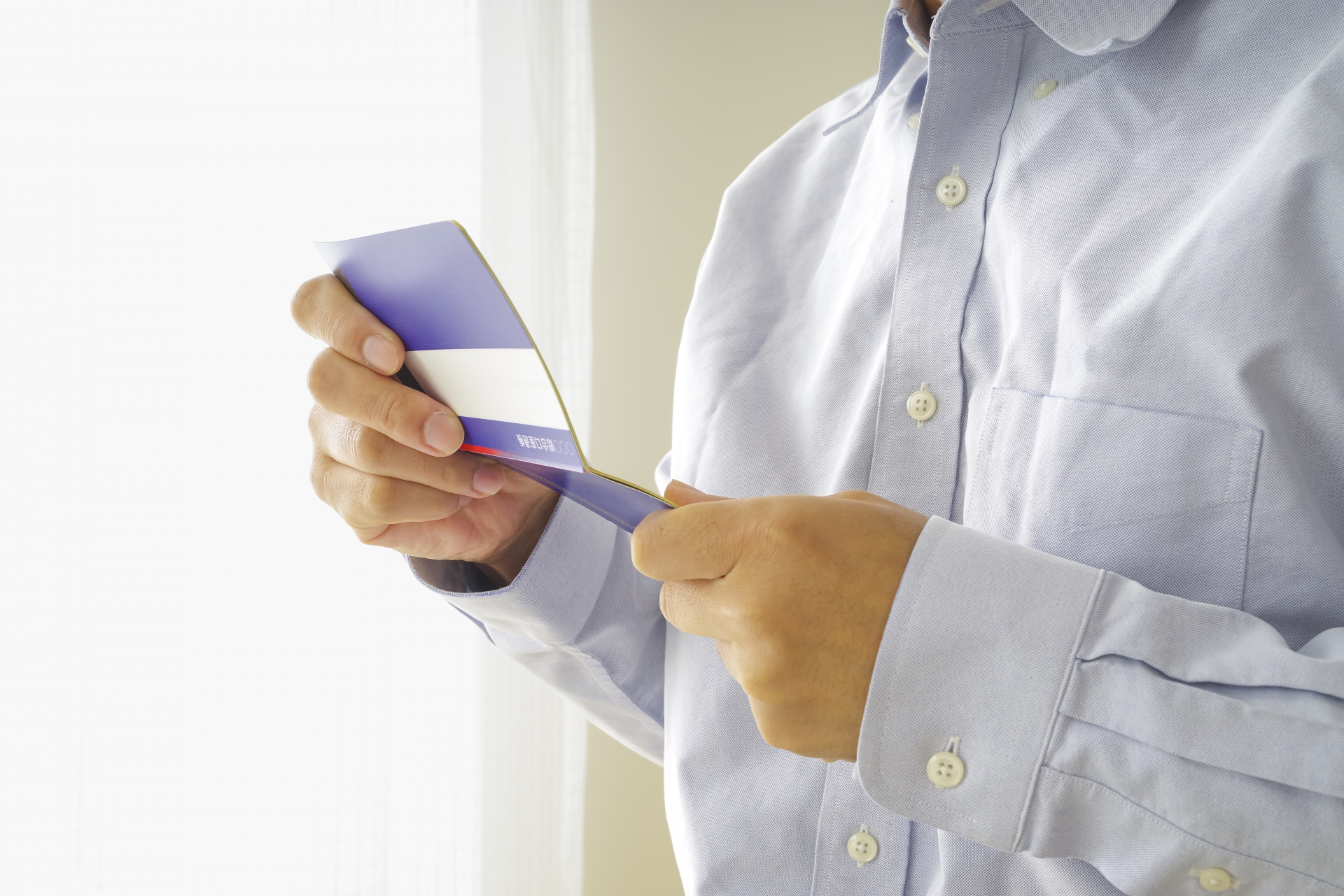 貯金通帳を見つめる中年男性