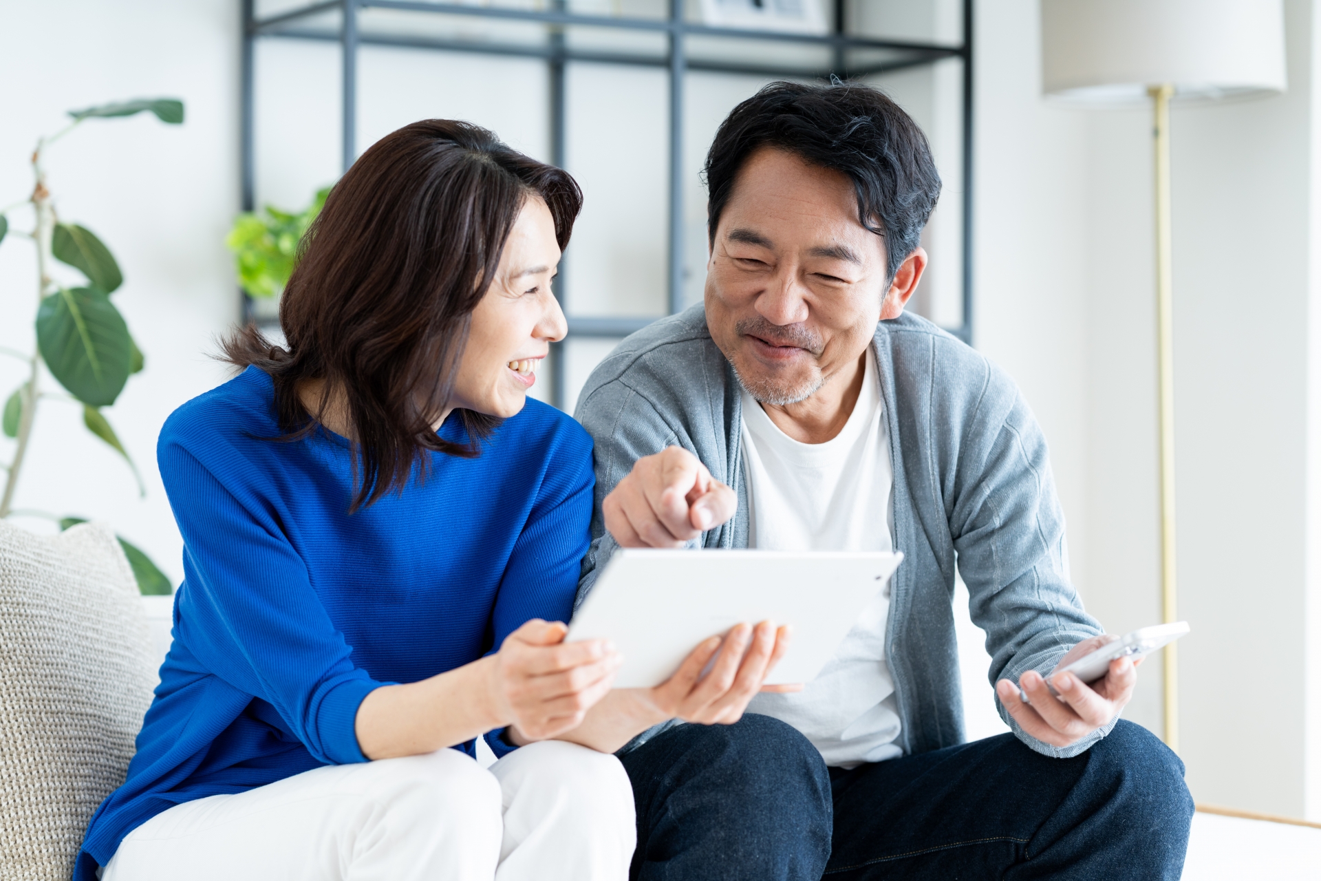 リビングでタブレットを使うミドルの夫婦