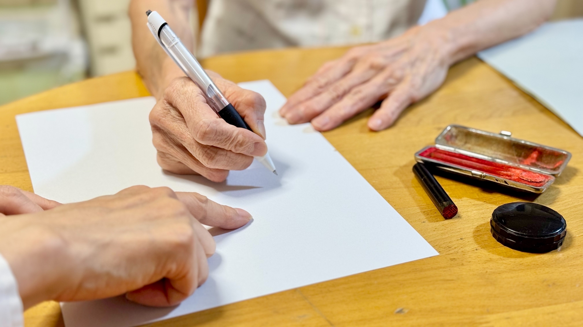 高齢女性に記入箇所を指示する女性と印鑑