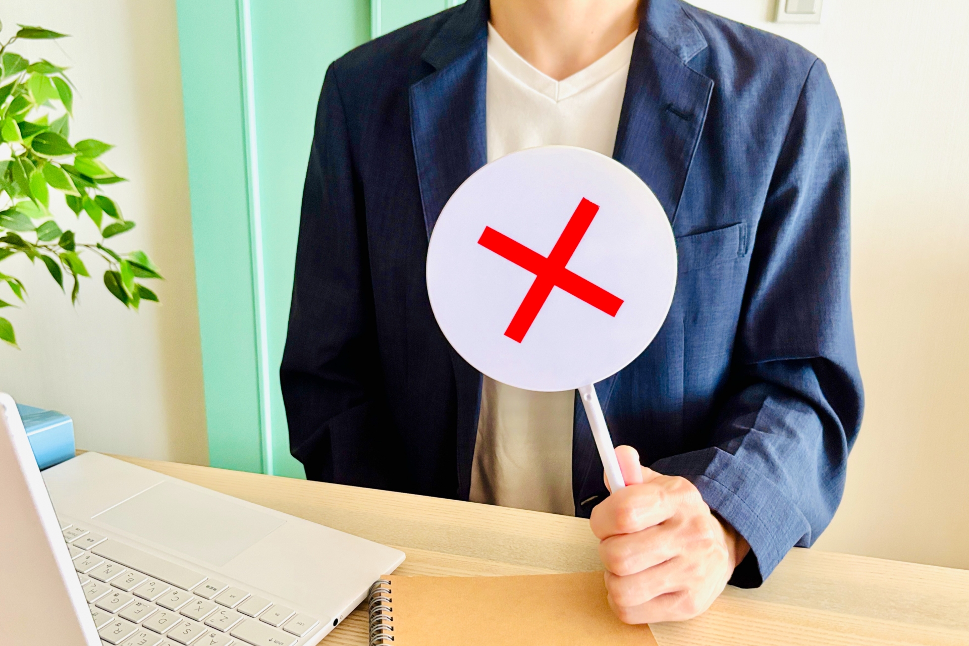 バツマークのプラカードを出す男性