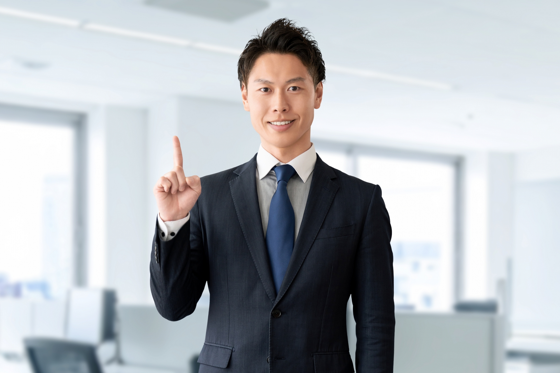 人差し指を立てるスーツの男性