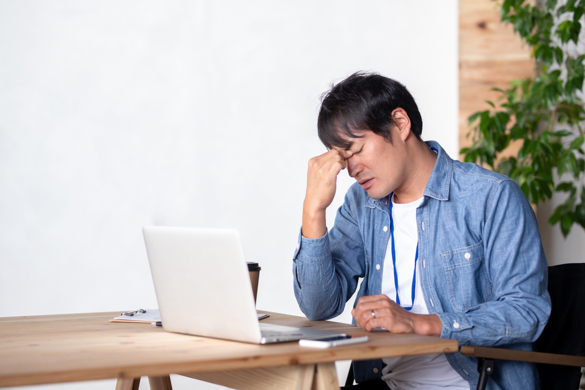 PCを見ながら眉間に手を当てる男性