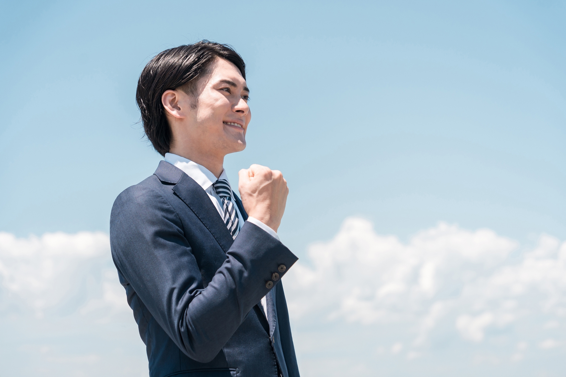 青空の中ガッツポーズするビジネスマン
