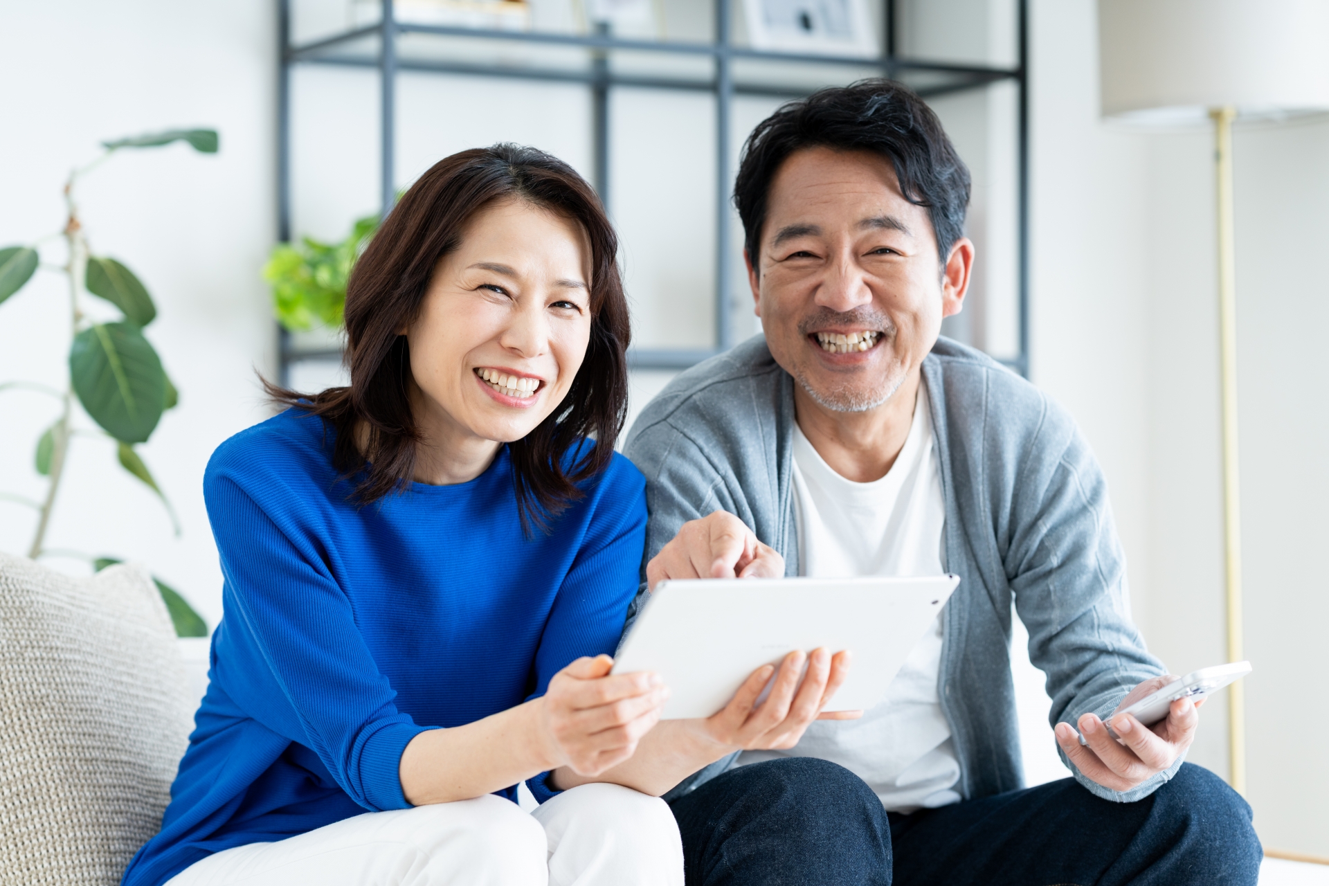 リビングでタブレットを使うミドルの夫婦