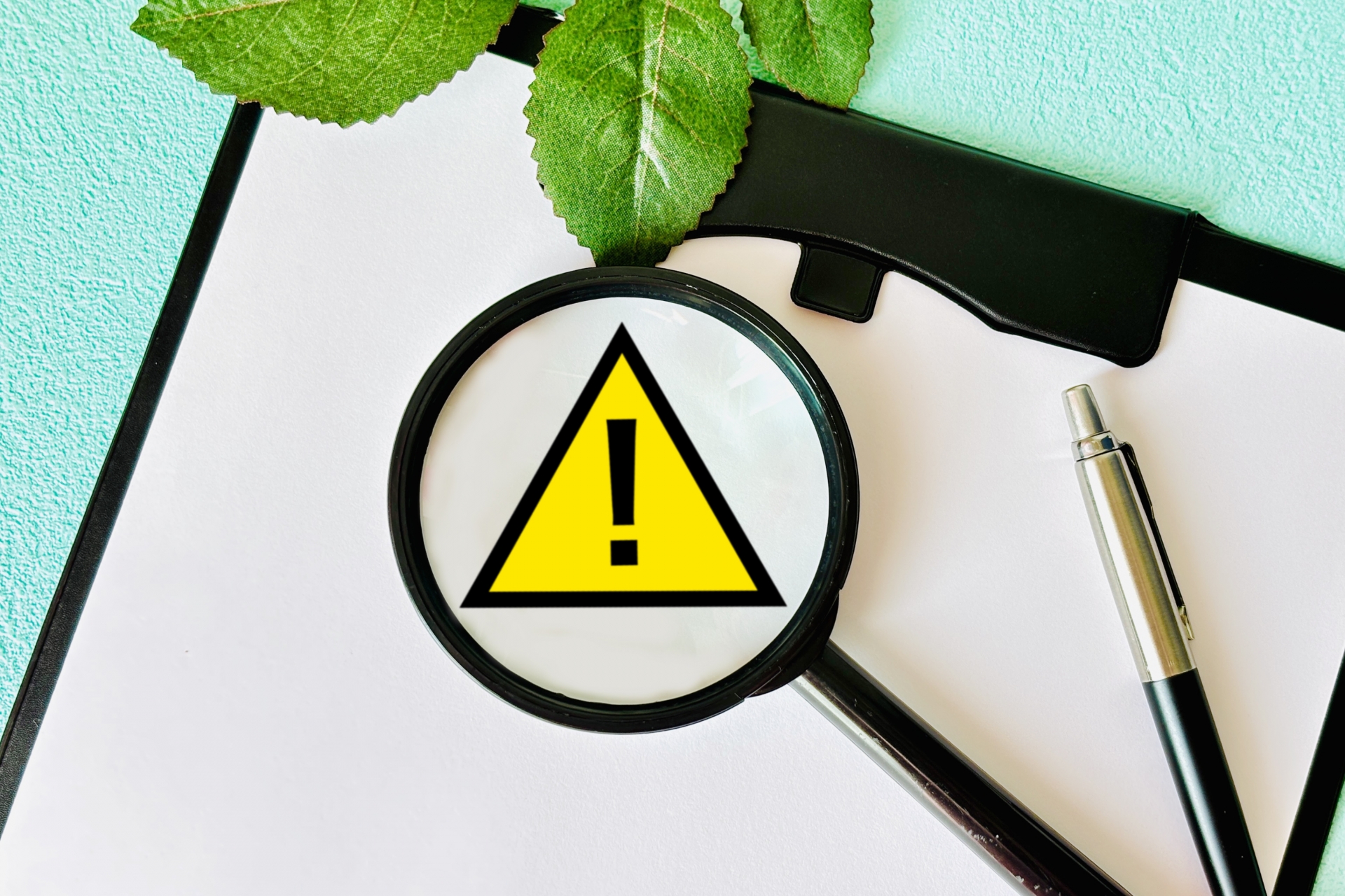 虫眼鏡と注意マークと水色バック