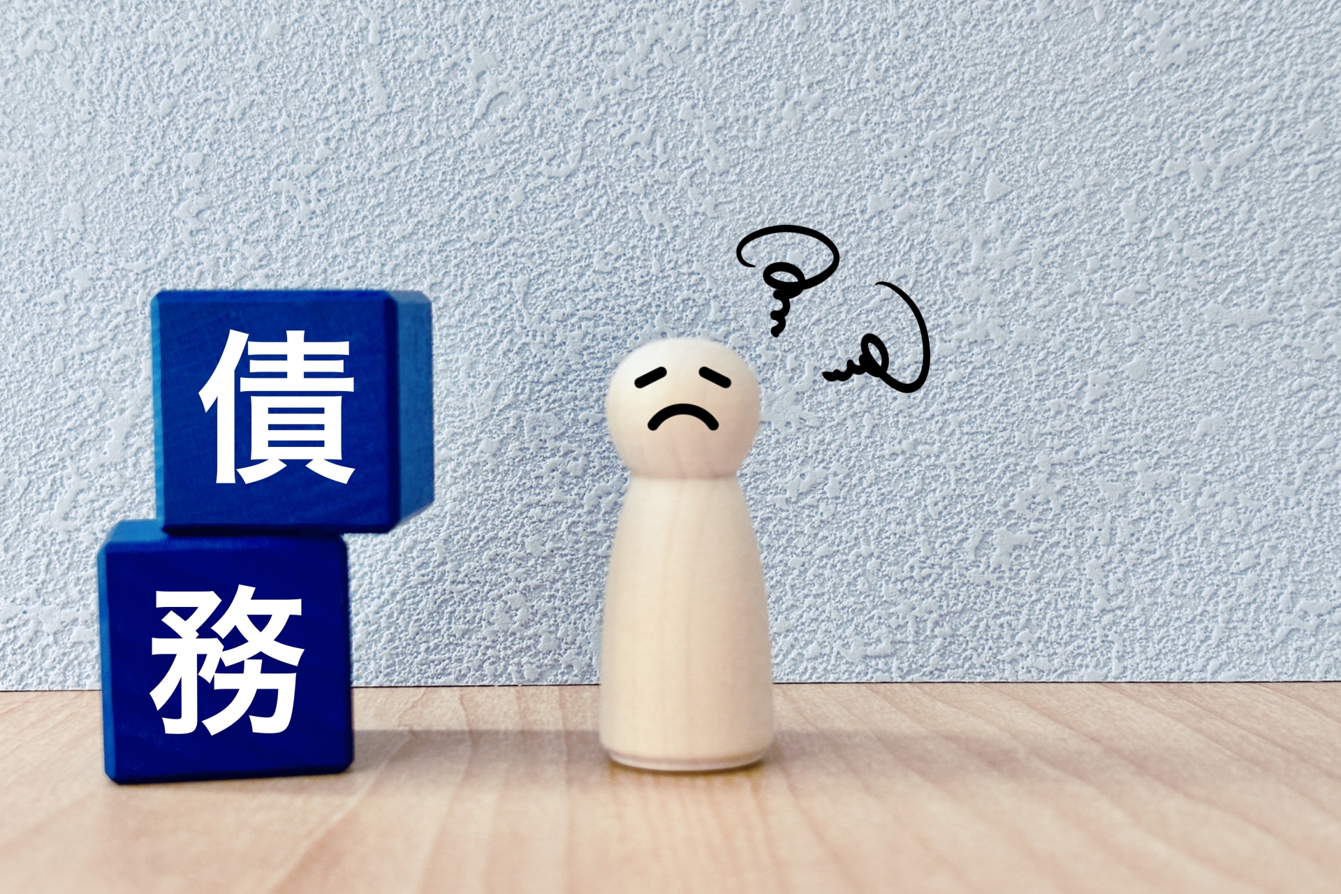 債務の文字ブロックと困った顔の人形