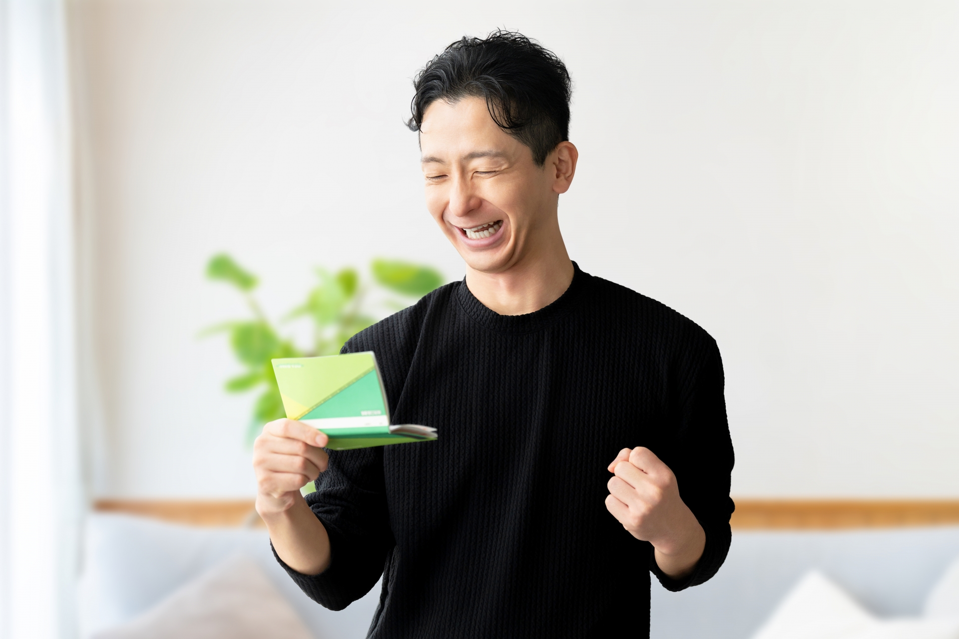 通帳を見てガッツポーズをする男性