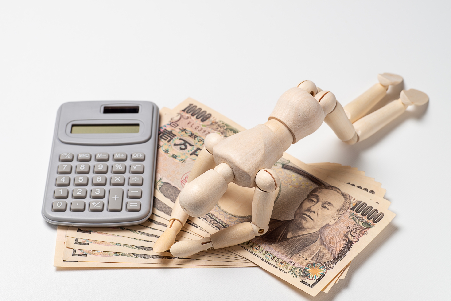 一万円札の上でがっくりするデッサン人形