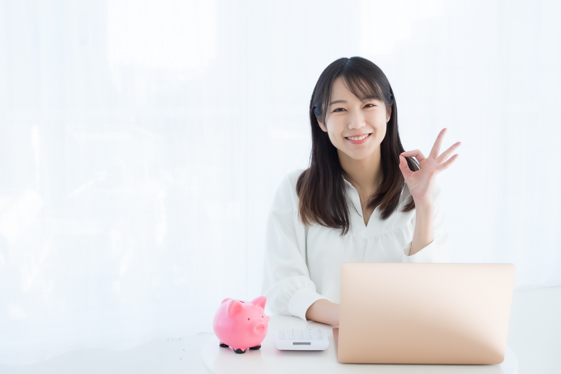 OKサインをする女性と豚の貯金箱