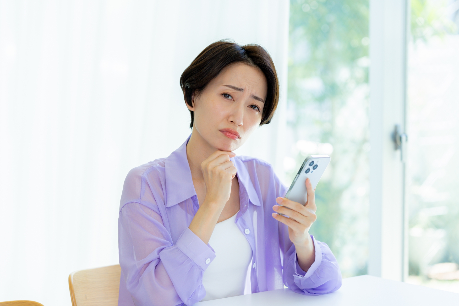 スマホを持って悩む女性