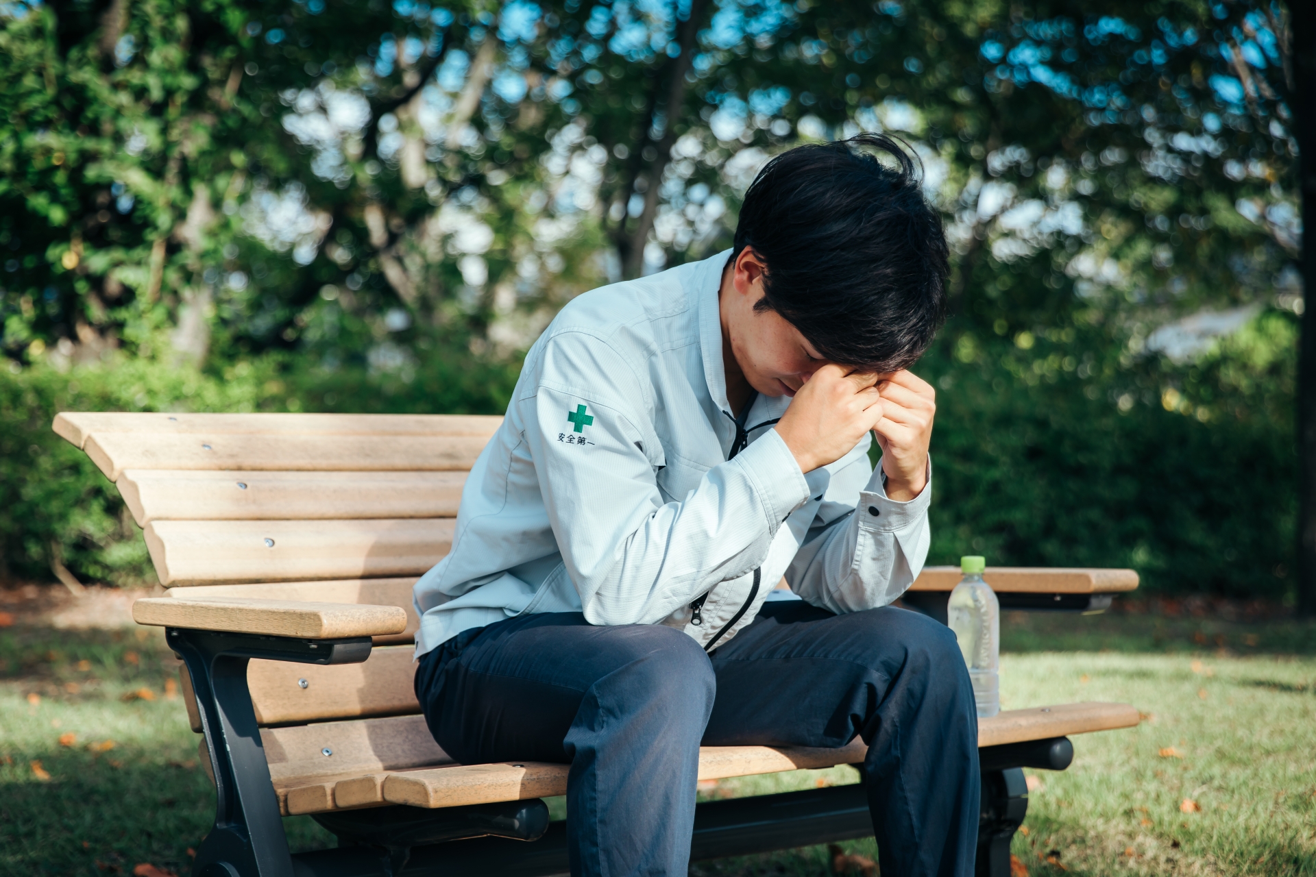 頭を抱える作業着の男性